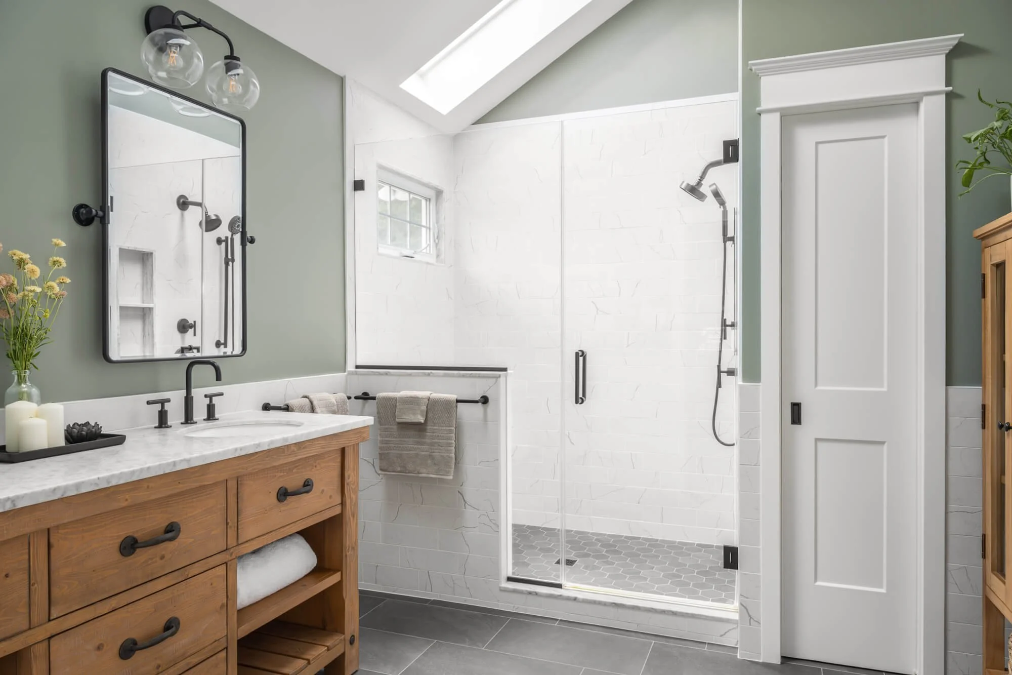 Farmhouse style primary bathroom with a wood vanity, matte black fixtures and white shower tile.