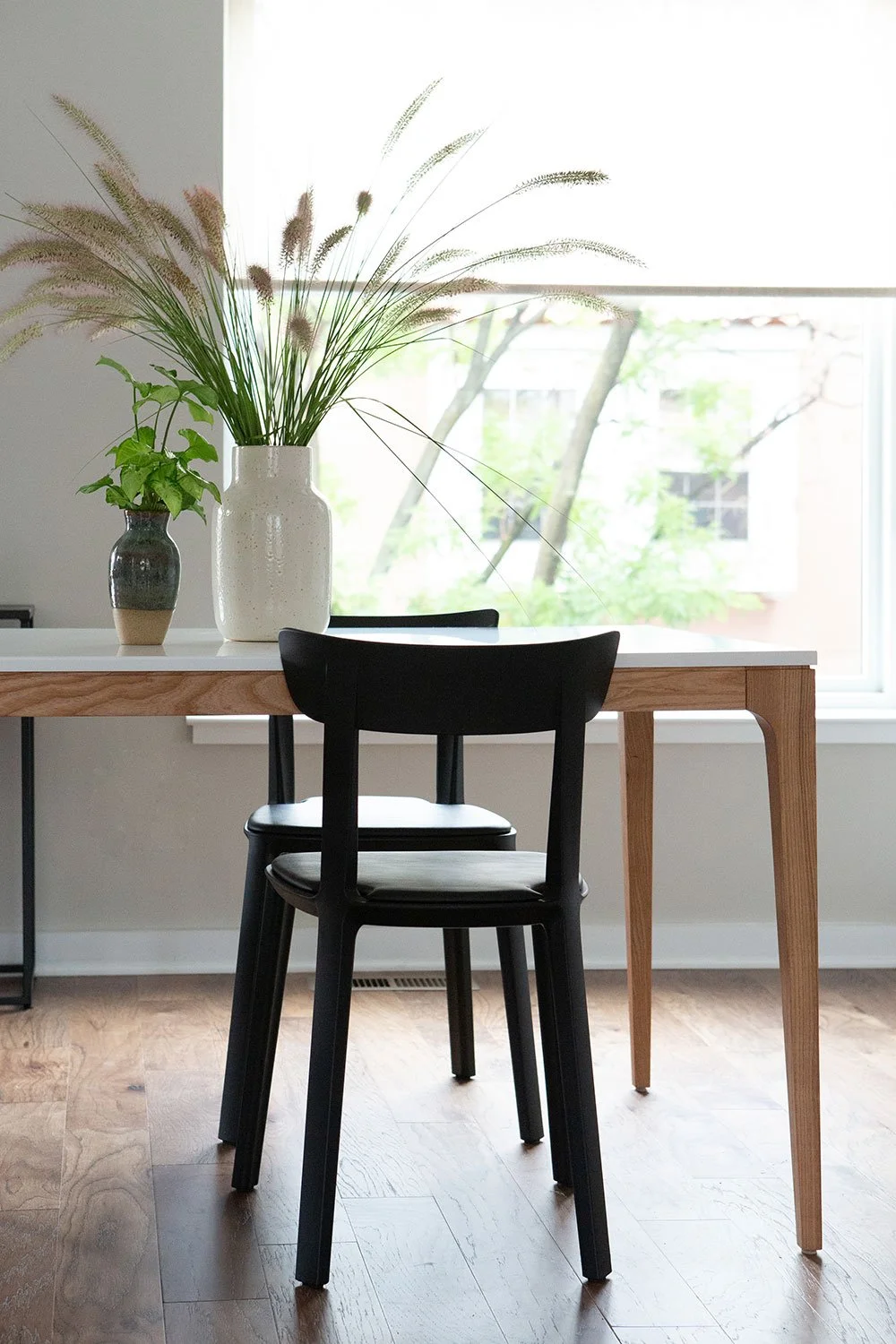 Light wood dining table with black dining chair.