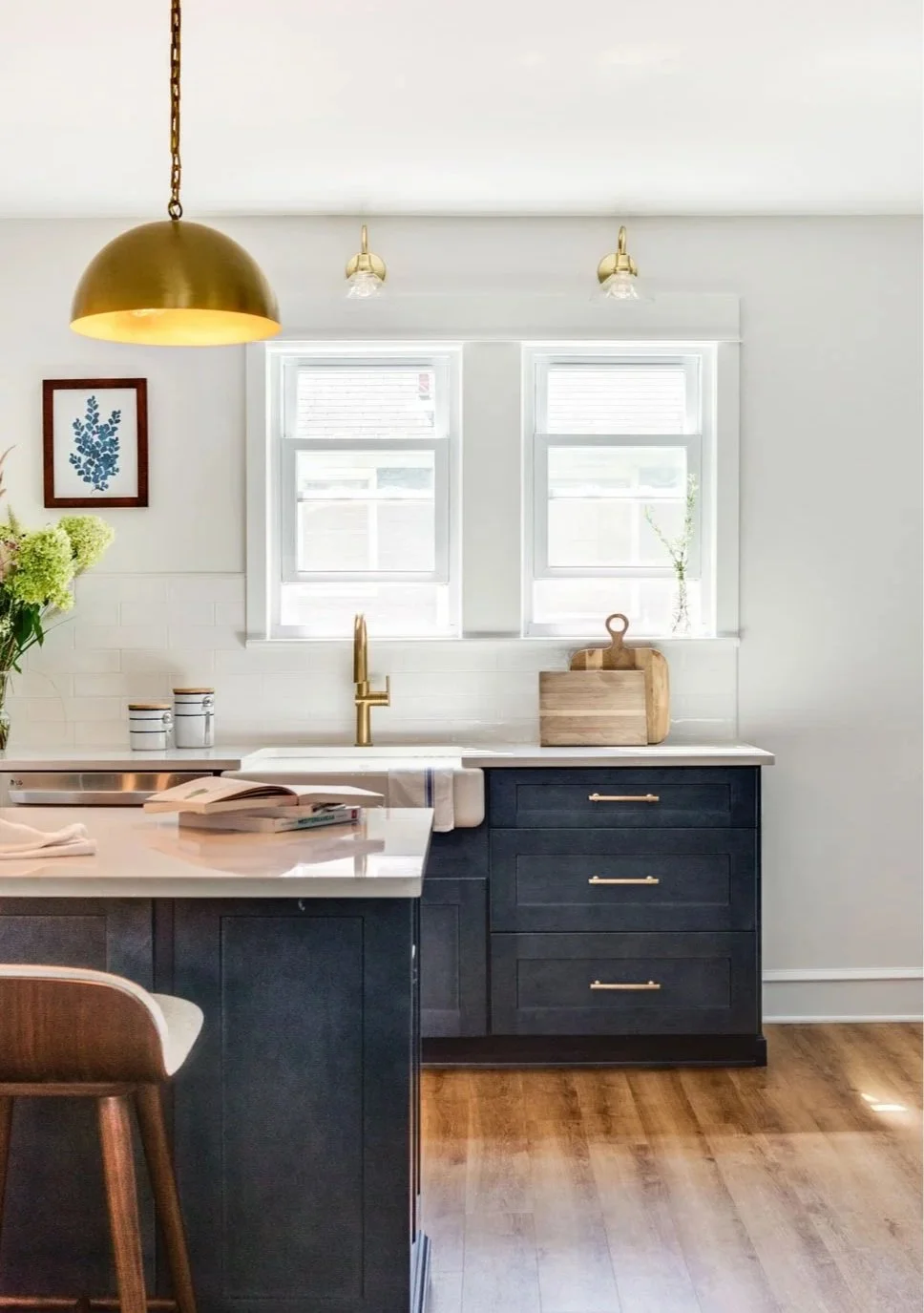 Kitchen sink under a window. Above the window is a brass sconce.