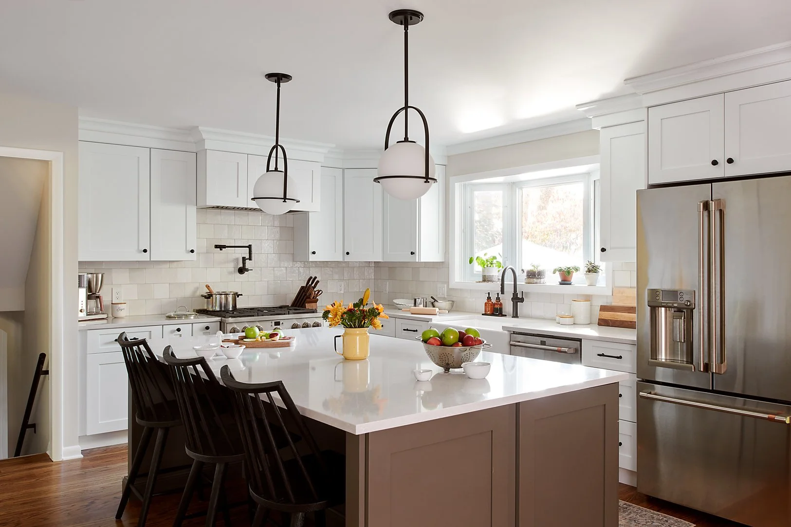 Large kitchen island in a warm charcoal gray which contrasts white perimeter cabinetry.