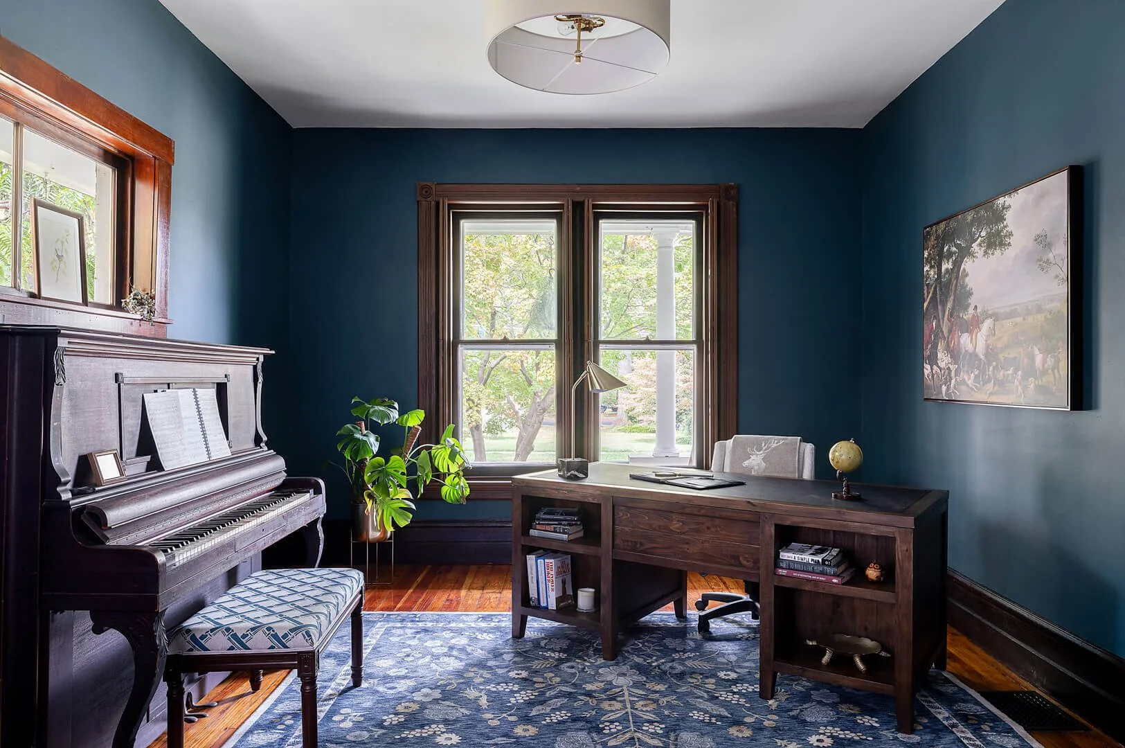 A study with dark blue walls and dark woodwork.