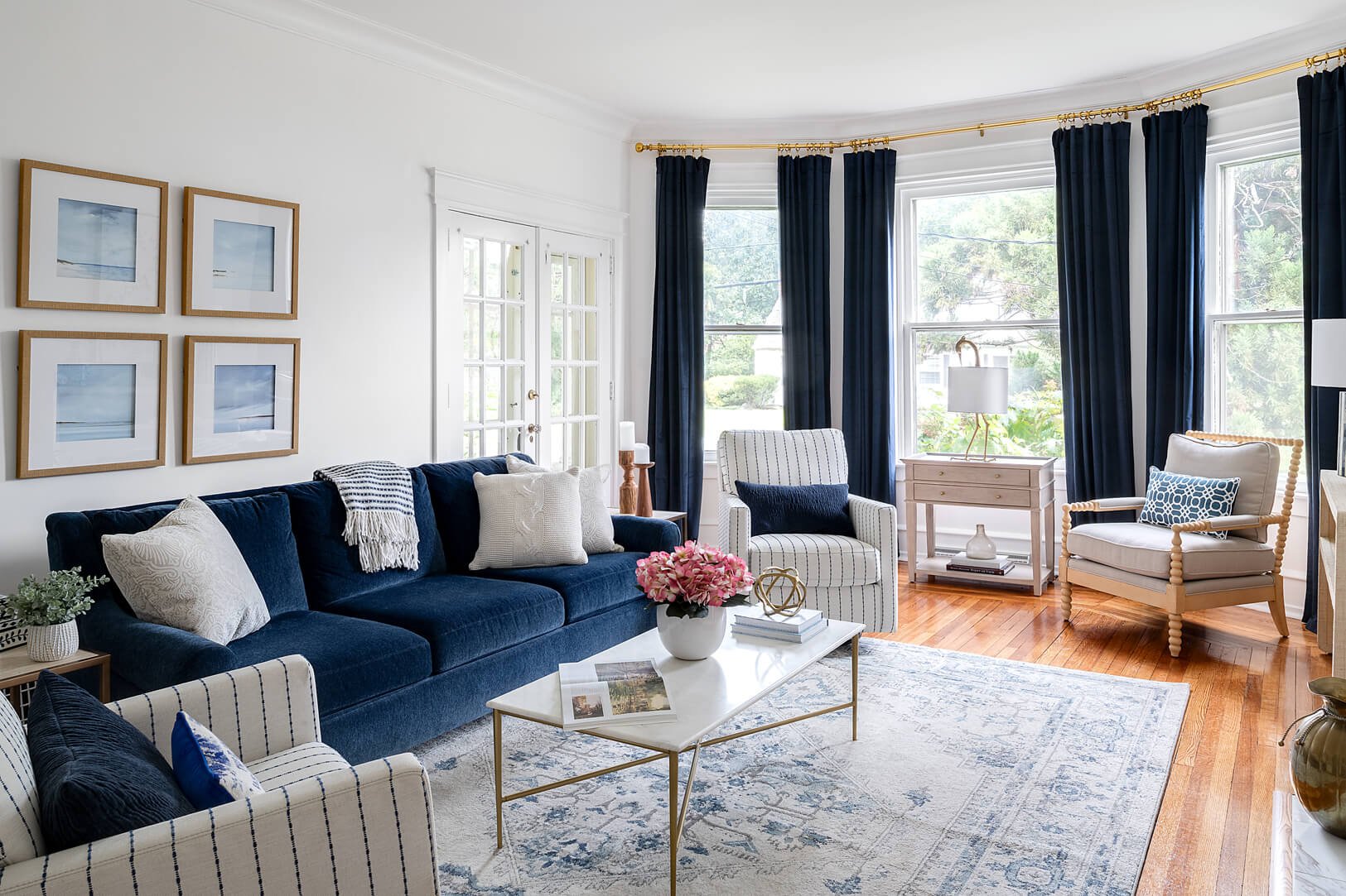 Large living room with bay window. The sofa and drapery are in the accent color—navy blue.
