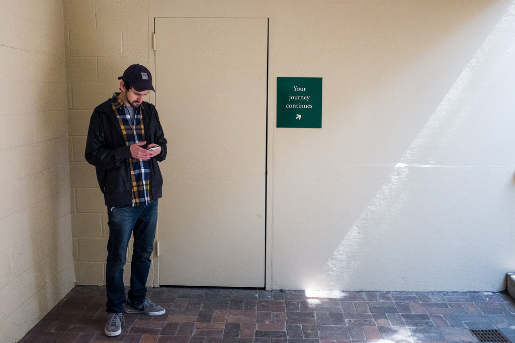 "Your Journey Continues" April 2014, New York Botanical Gardens, Bronx, New York Fujifilm X100s, 23mm, f/11, 1/125, ISO 5000 I take it back. Maybe there are two instances in history where a guy checking his smartphone has improved a photo. I may be the only photographer to ever visit the New York Botanical Gardens and come away most excited about a photo of a guy in front of a beige cinderblock wall, not a flower in sight. I don't do much in the way of social commentary in my work, but I just love this one. The guy, completely oblivious to the journey that lies ahead. The total blandness of this space. The polite sign trying to encourage him on to bigger and better things. The ray of light from the heavens beckoning him on to something unimaginably amazing. He's blind to it all. Right now, there's candy to be crushed. 