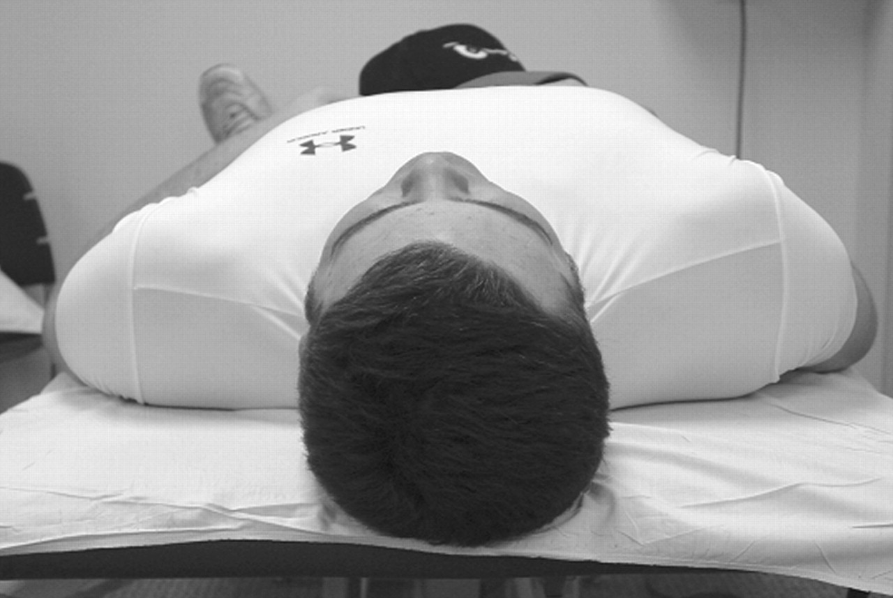 An image of a baseball athlete with tight and/or overdeveloped anterior chest/shoulder muscles on the right side. Notice how his right shoulder lifts up and off the table. Anterior/posterior imbalances like these can be caused by an incorrect push-to-pull movement ratio.