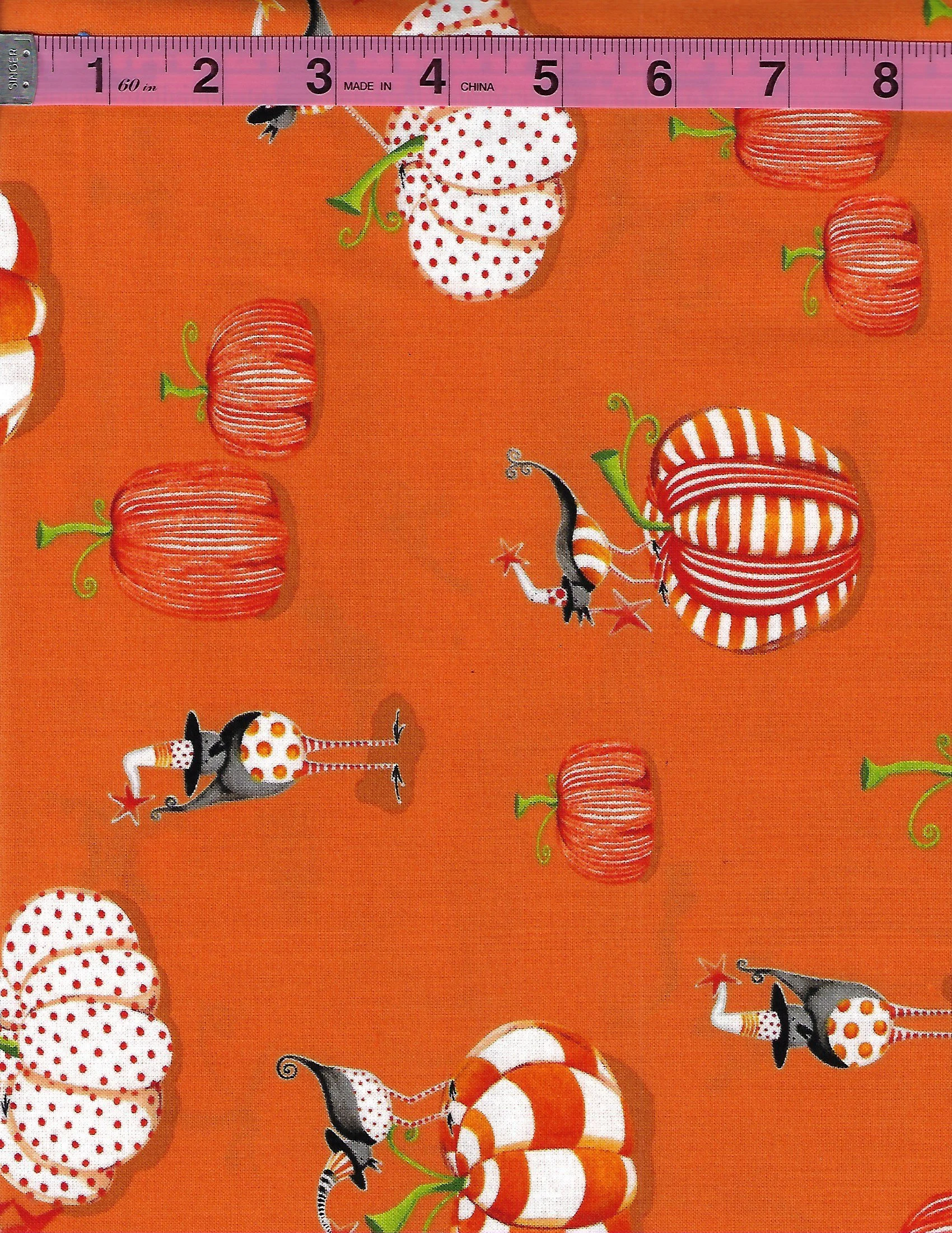 Henry Glass Delightfully Frightful Halloween fabric featuring orange pumpkins, whimsical witches, candy corn, and spooky accents on a vibrant orange background.