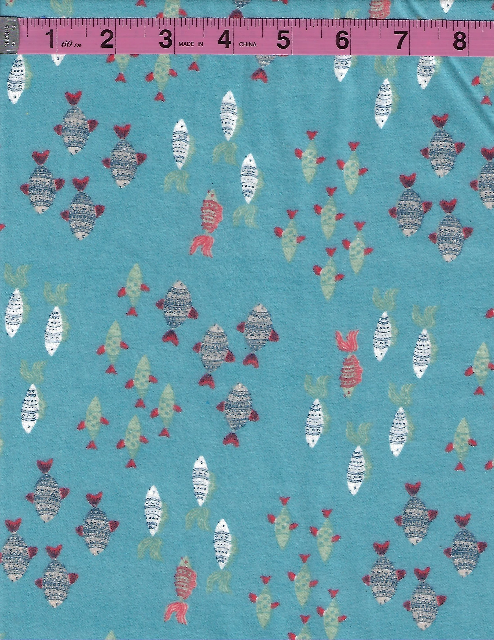 Turquoise cotton flannel fabric with colorful white, gray, coral, and green fish scattered across a blue background