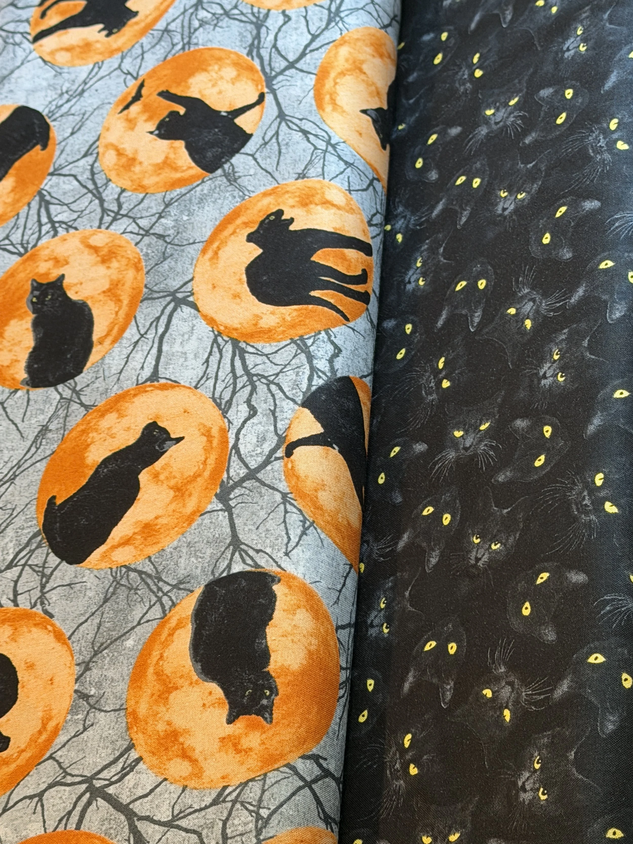 Halloween cotton fabrics featuring black cats on orange full moons and black cats with glowing yellow eyes