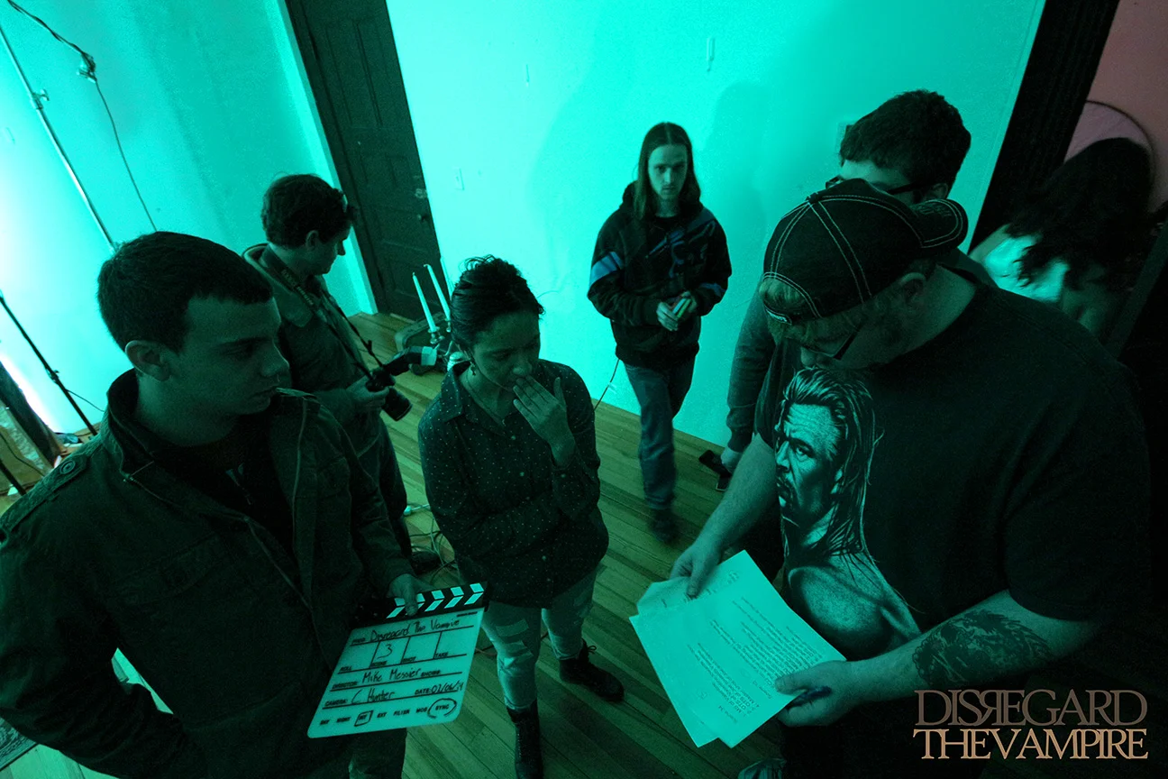 Crew members gather around writer, director and producer Mike Messier to discuss the next scene for Disregard The Vampire, 2014.