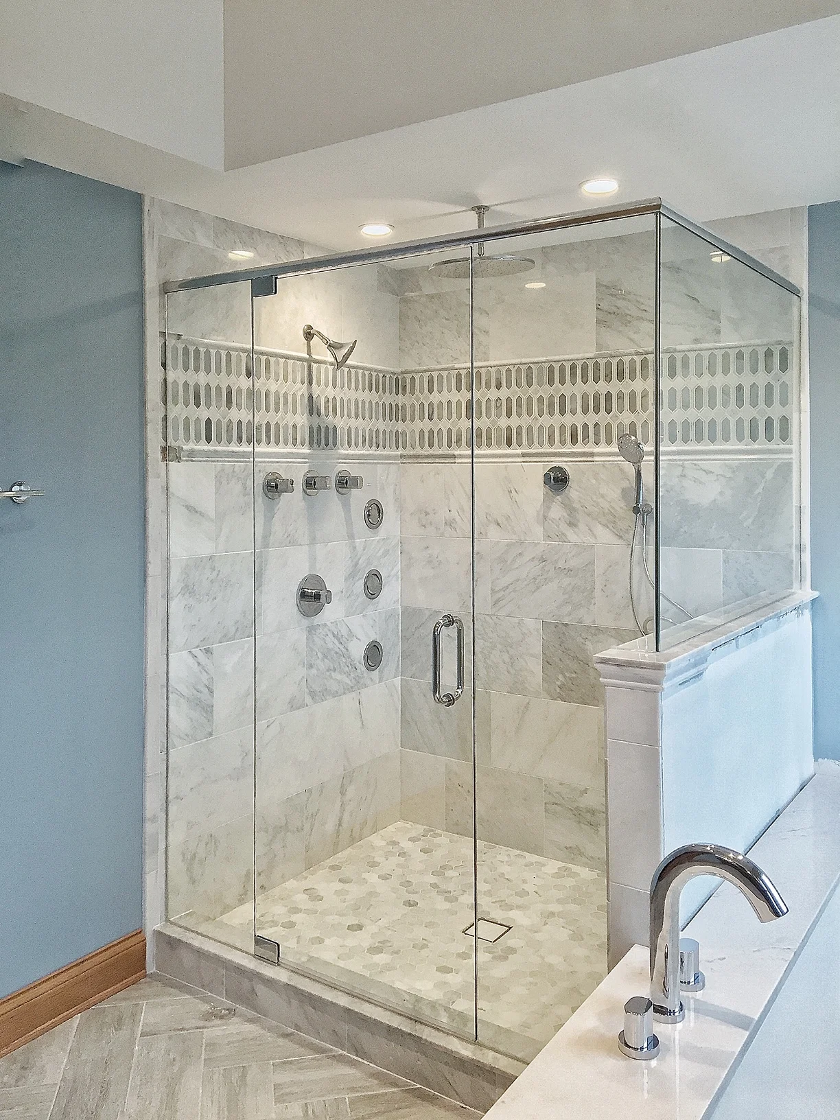 Custom marble shower with body sprays, rain head and herringbone floor by Hawthorn Development Hawthorn Woods, IL