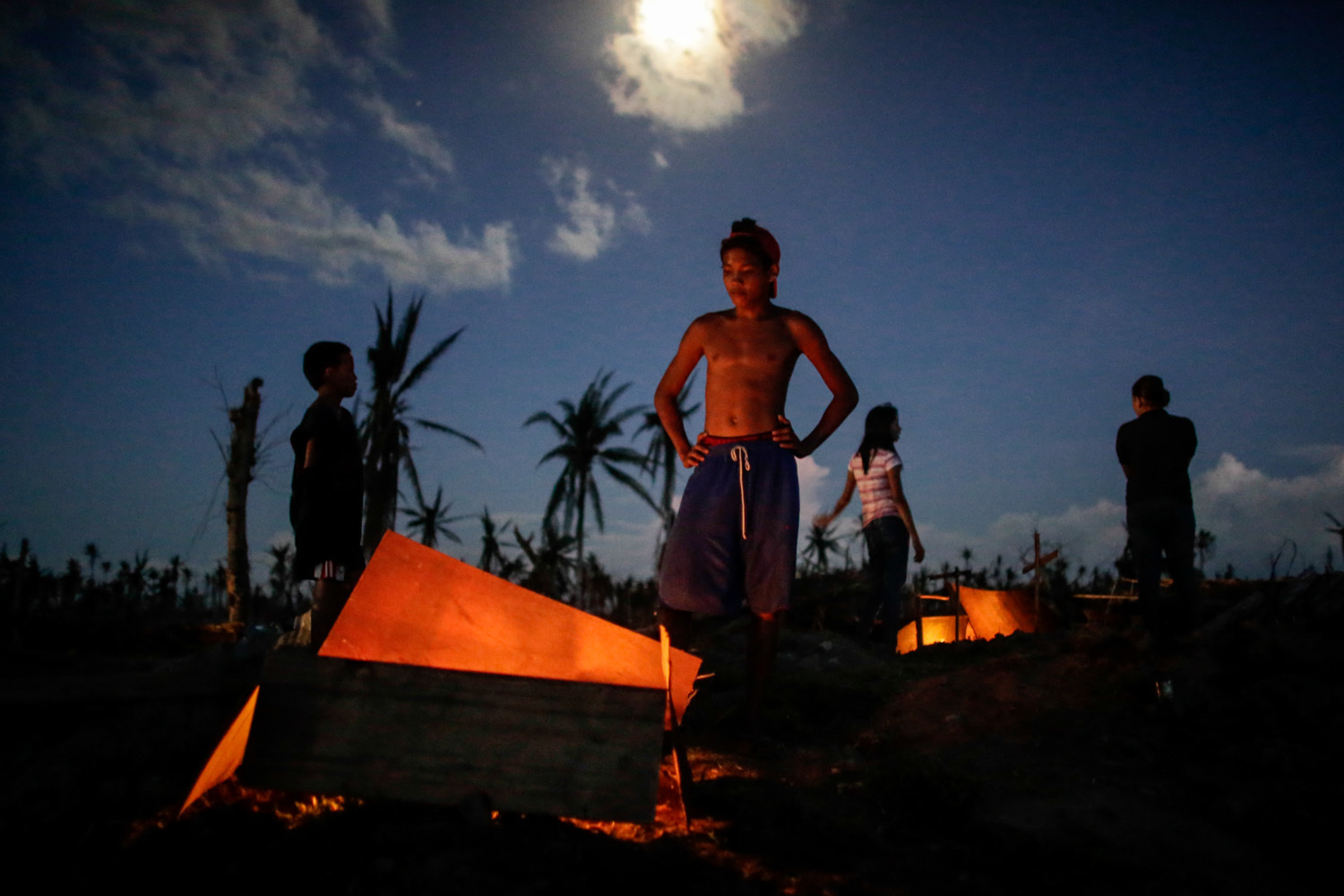  Survivors mourn their relatives who they buried in a mass grave along a highway during the third week after Haiyan hit the province of Tanauan Leyte. It was only during the weeks after were they able to mourn as they had to fight for their survival 