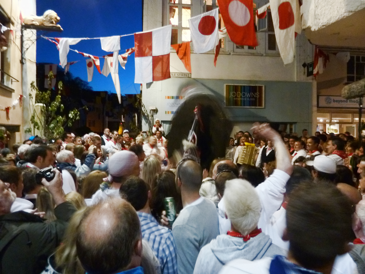 Outside the 'Golden Lion' pub, home of the Oss. The Oss - the blurred black shape - tilts and whirls in a last frenzied dance while the people of Padstow bellow out the final renditions of the MayDay Song, with tears visibly welling in their eyes, as they watch the Oss finally be put to sleep for another year.
