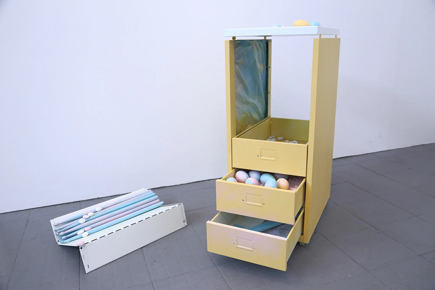 Compartmentalising the S(h)elf Part 1(a): Untitled (self portrait) Percussive reassembled filing cabinet on wheels Materials: reassembled metal filing cabinet on wheels, acrylic spraypaint, plastic drop sheet, percussion egg shakers, drum sticks, silicone vibrator, AAA batteries, almond oval sweets, pencil drawings, pencil on deck of index cards, textured foam