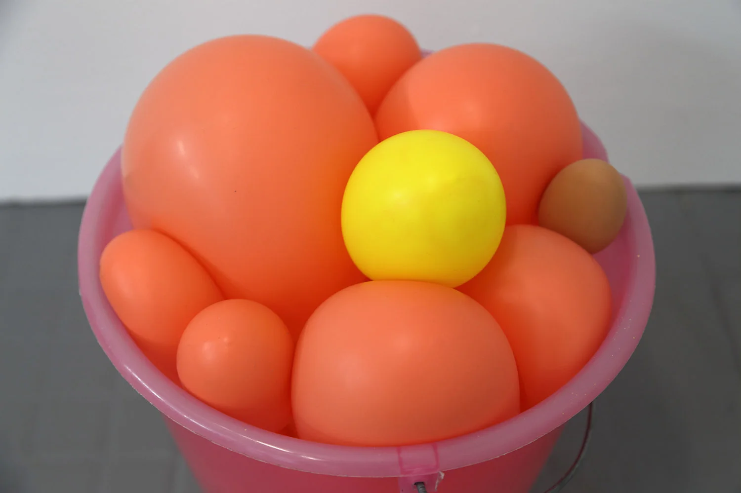 Materials: plastic bucket with metal handle, latex balloons, egg shaped rubber bouncy ball, sound (hidden mp3 player, looped, hidden mini speaker)