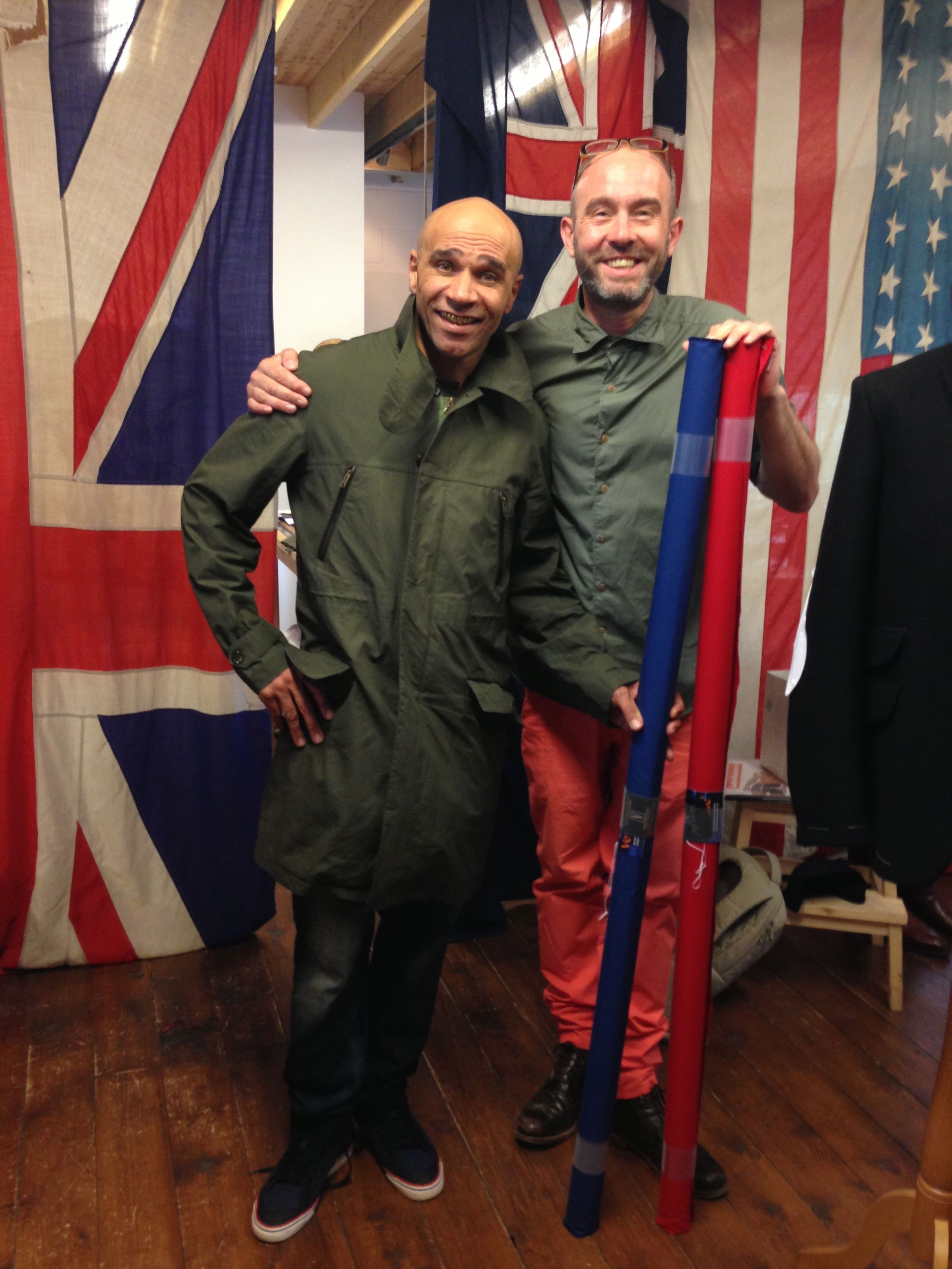 Goldie in his "Mr Wesley" mac with Mr Wesley, holding rolls of the British super water resistant closely woven breathable cotton wunderfabric Ventile (R) from which we make our macs.