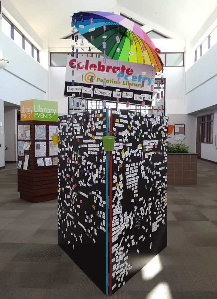 The finished display had a rainbow umbrella with words cascading down from its edges attached with fishing line. A custom sign was created as a call to action for patrons to come and create.