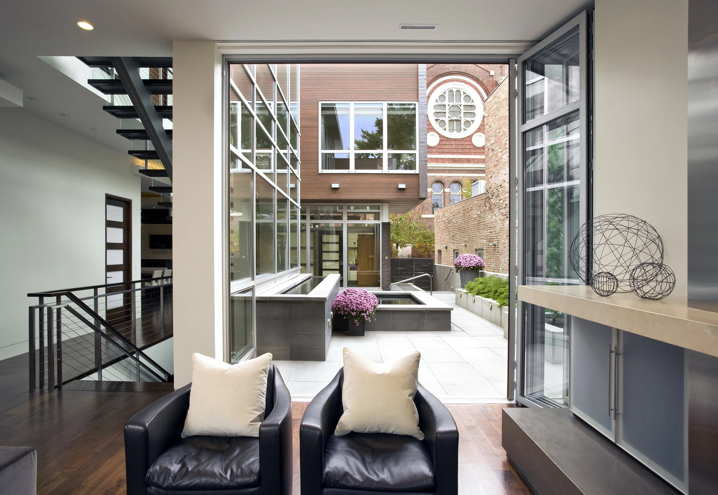 Folding glass wall opens the family room to outdoor seating pool access at the Cortland Residence