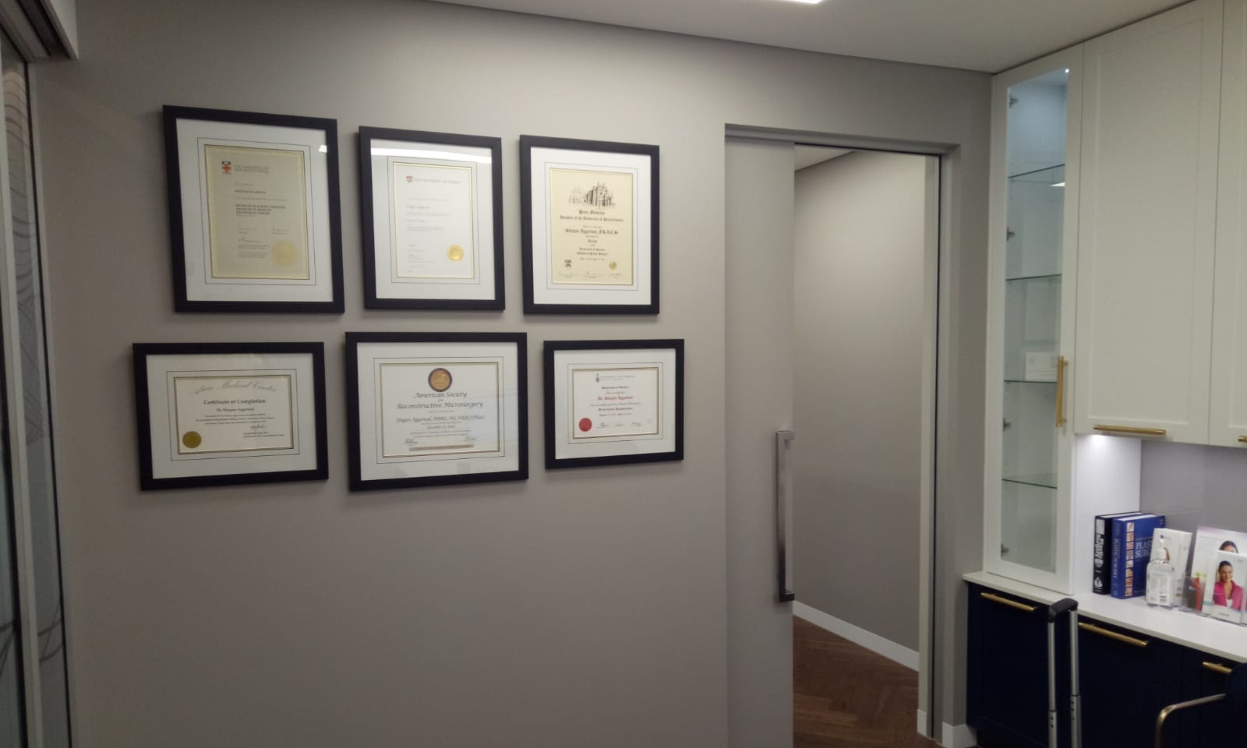 Gallery wall of professionally custom-framed university degrees and certificates at Art Reflection, Mosman.