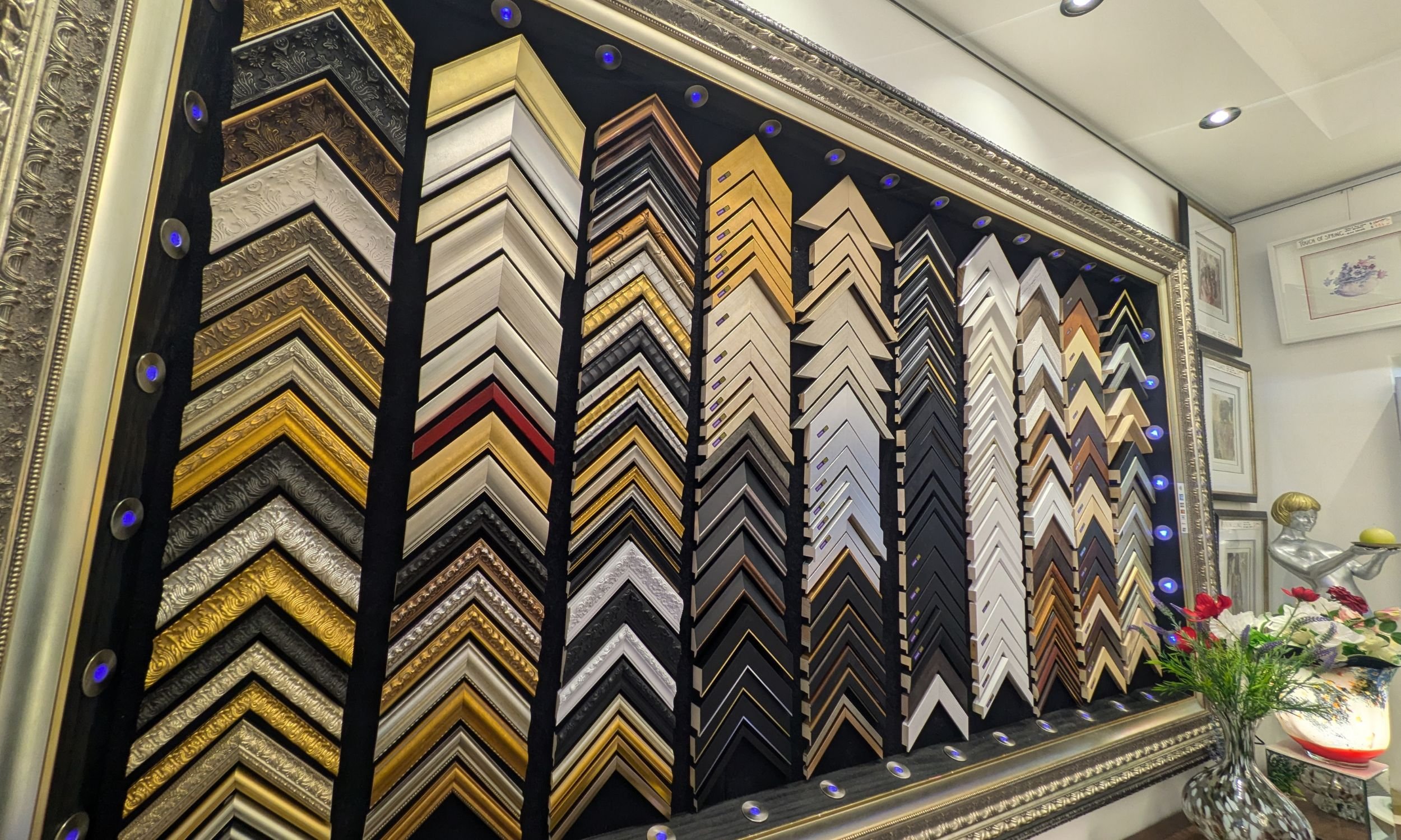 A wall display of diverse custom picture frame samples at the Art Reflection gallery in Mosman, showcasing various styles, textures, and finishes for original artworks.