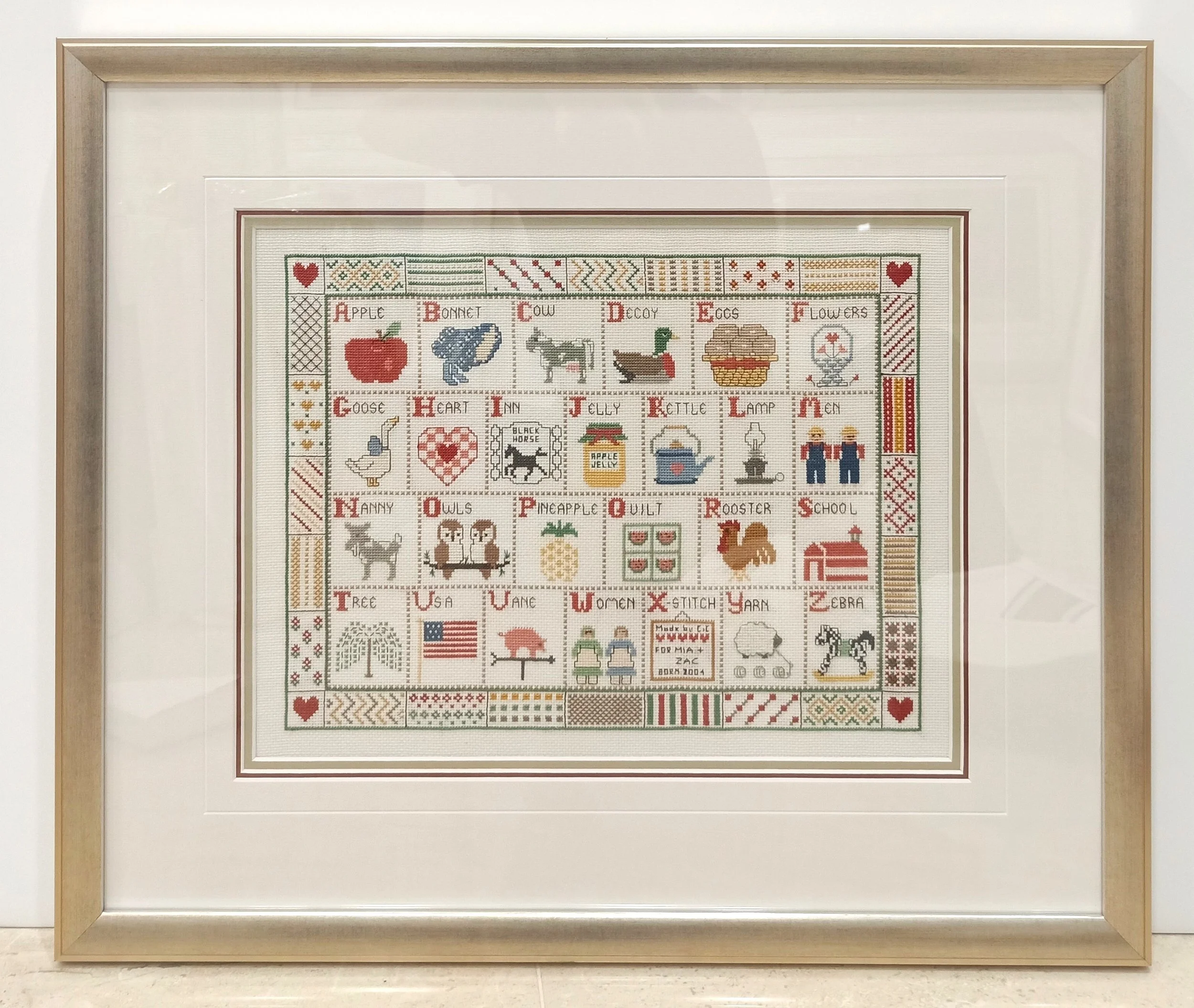 Professional textile framing in Mosman featuring a hand-stitched sampler tapestry in a custom cream timber frame with archival mounting.