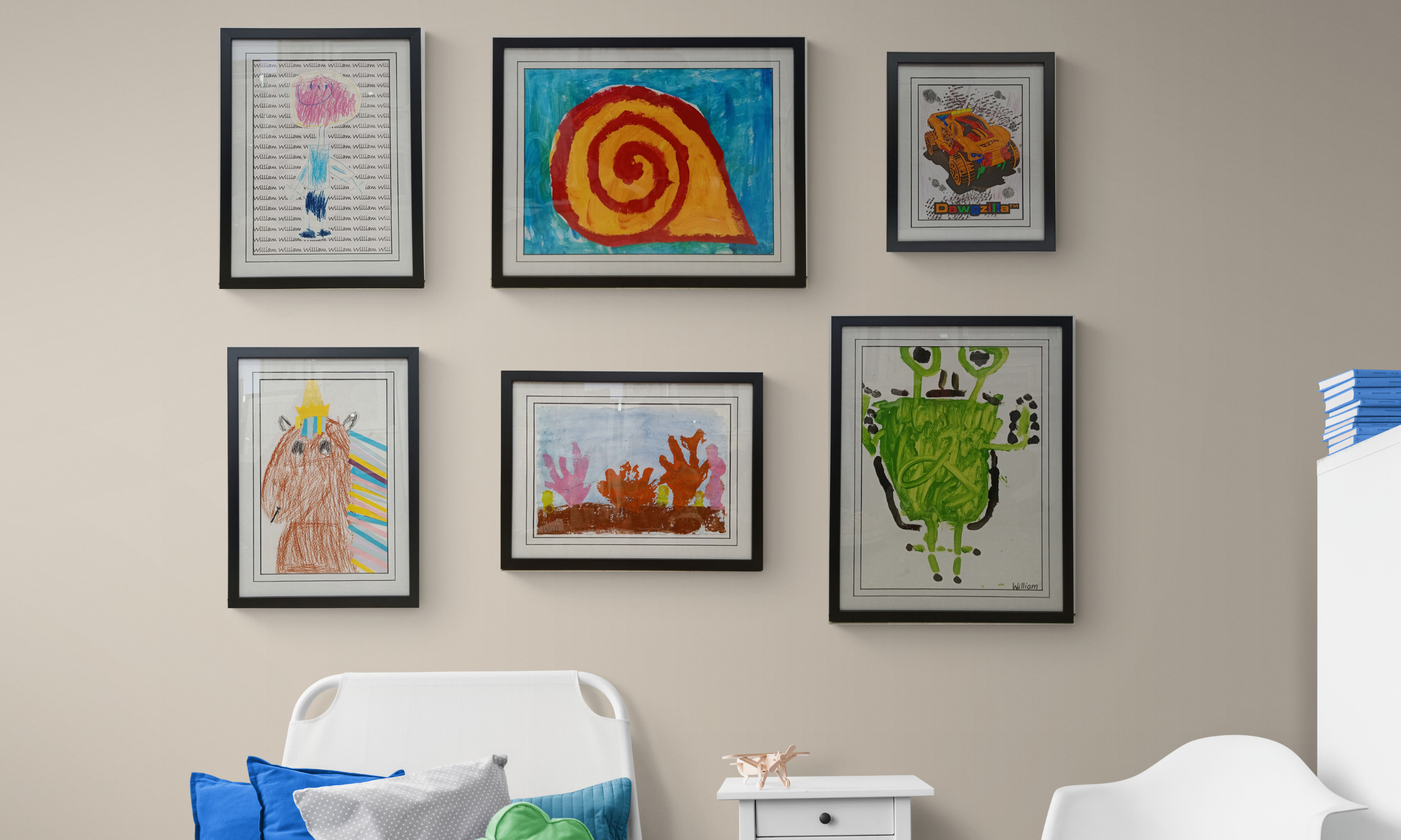 A professional gallery wall featuring various children’s drawings and paintings, each custom-framed with archival matting at Art Reflection in Mosman.