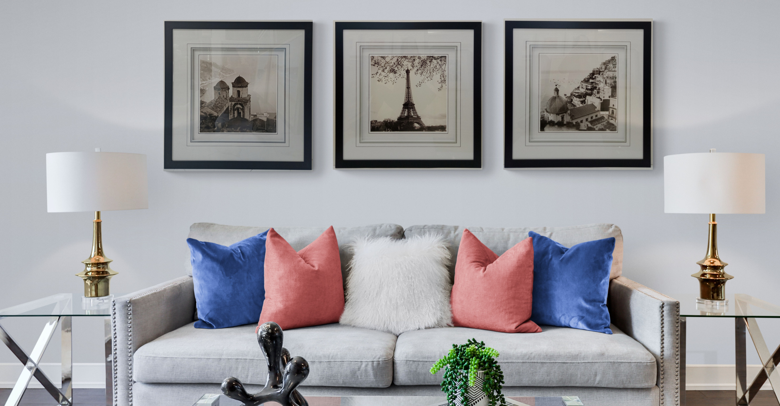 Three custom-framed black and white architectural and landscape photographs displayed symmetrically on a wall above a living room sofa.