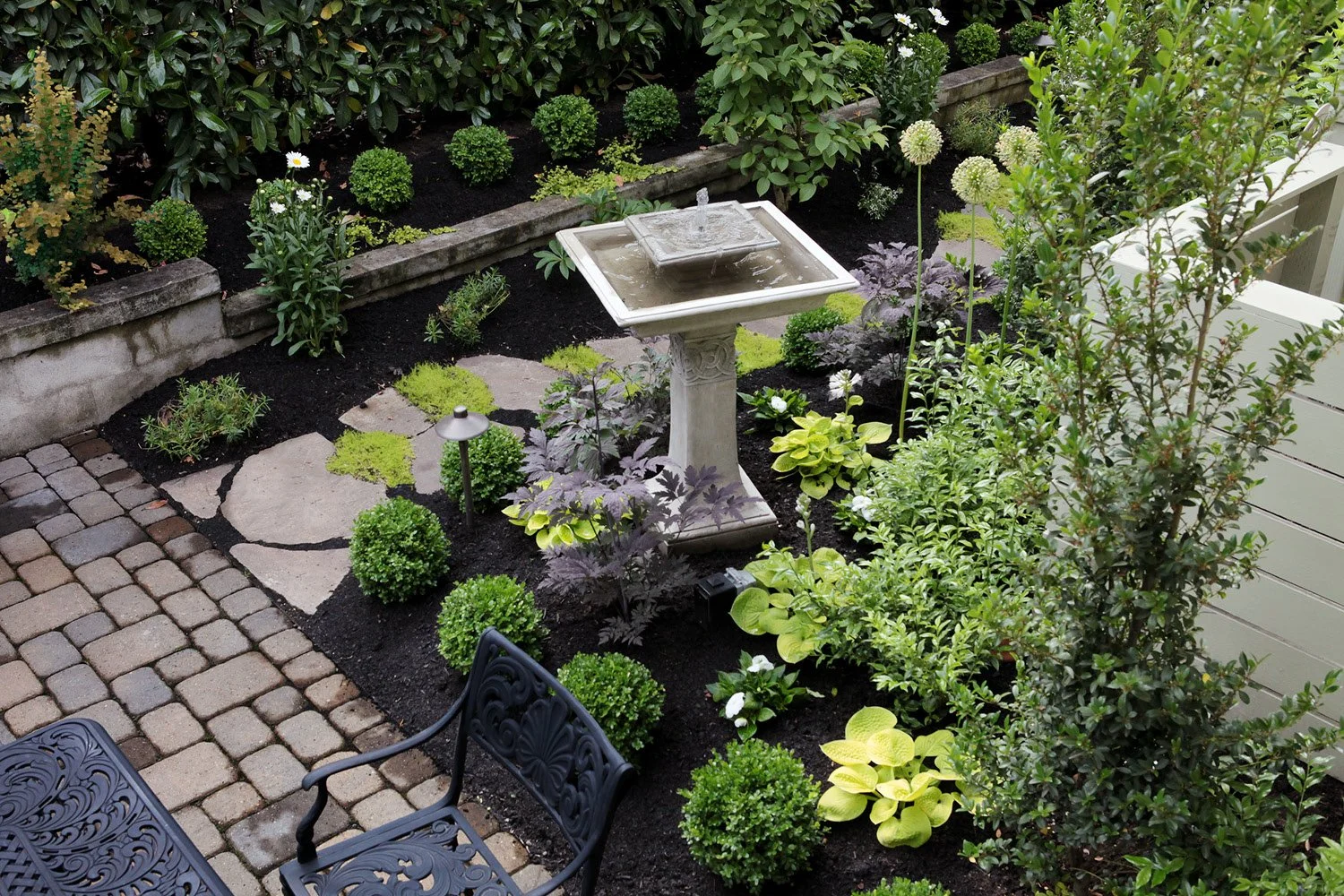 Traditional style landscape for a craftsman home in Vancouver, Washington. This corner is where the side yard meets the backyard. Now the homeowners have a lovely garden area to sit next to while dining alfresco. We designed a white garden of shasta 