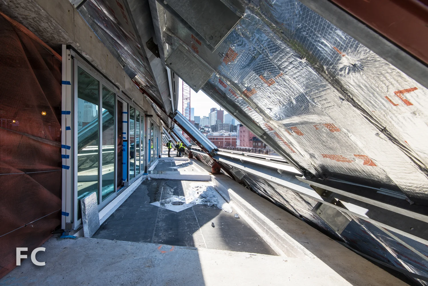 View of the sloped facade's structure and window wall under construction.