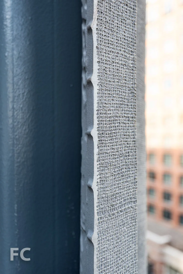 Burlap imprint on the street face of the facade screen.