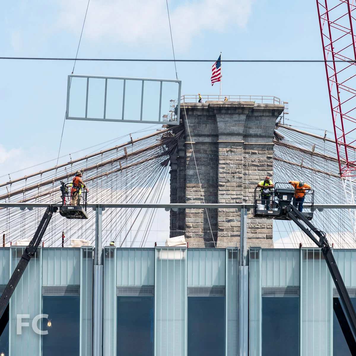 A glass wall panel being hoisted into place.