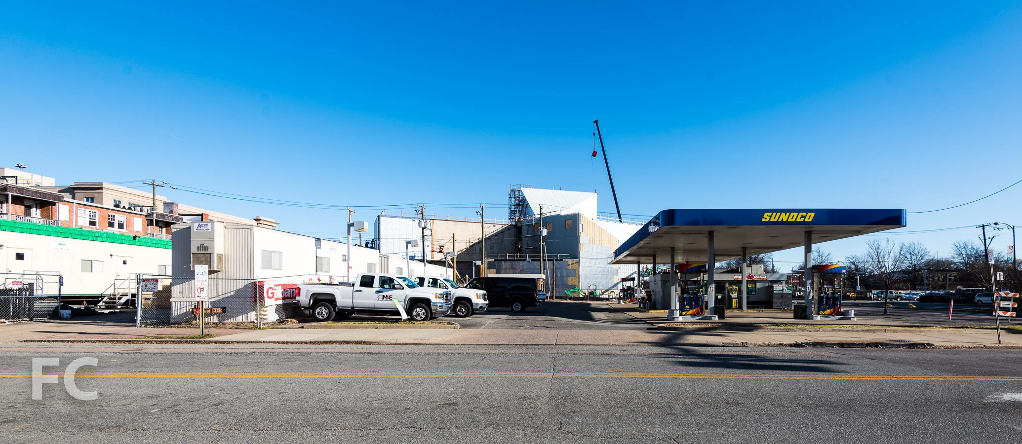 View from West Grace Street, with an existing gas station in the foreground and the west facade rising in the background.