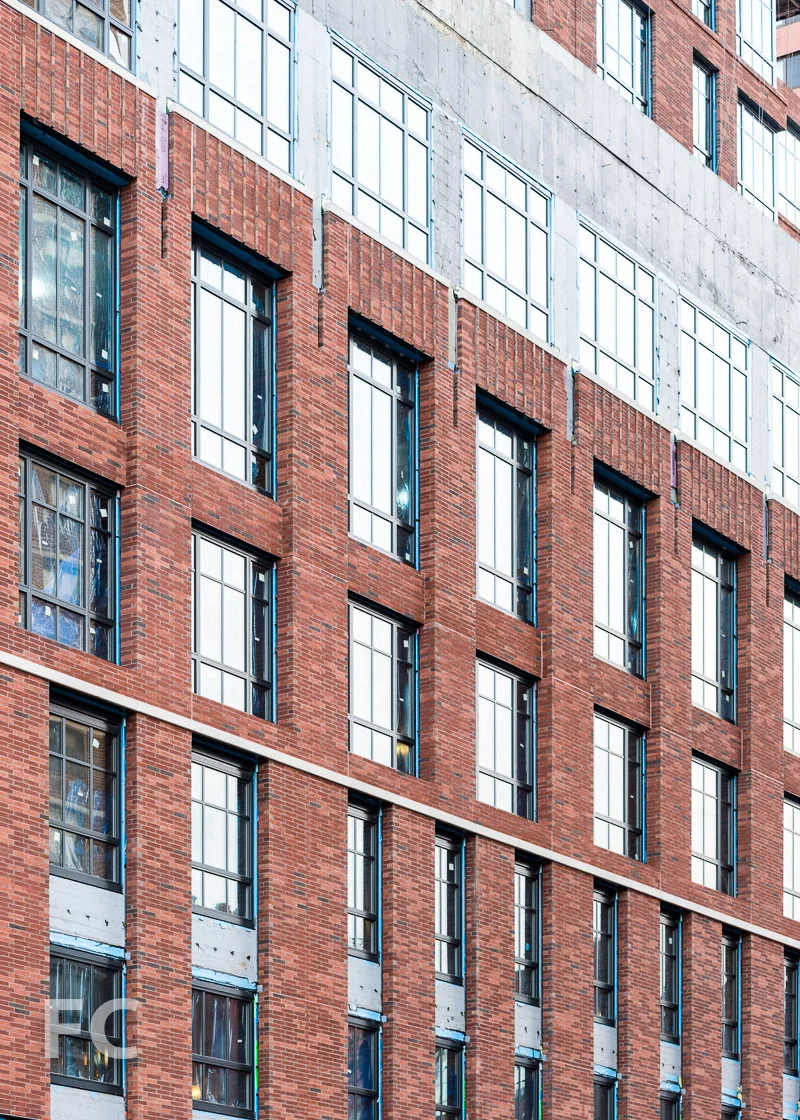 Close-up of the brick and glass west facade.