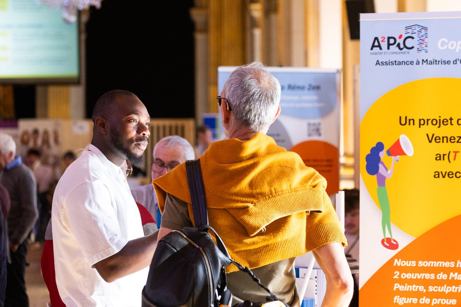 Échange entre un exposant et un visiteur pendant un salon professionnel à Paris photographié lors d'un reportage événementiel