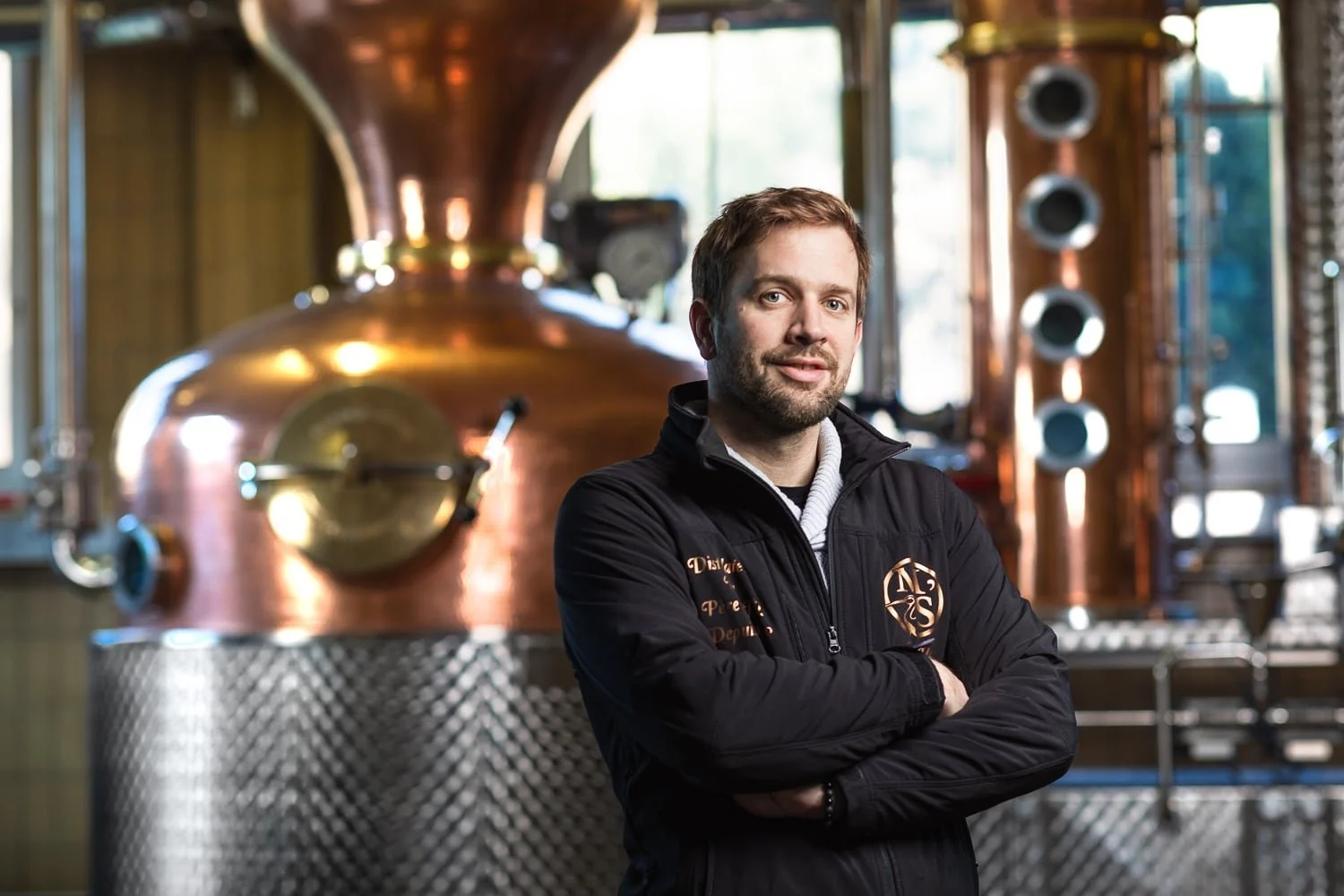 Portrait d'un producteur de whisky artisanal devant son alambic en cuivre