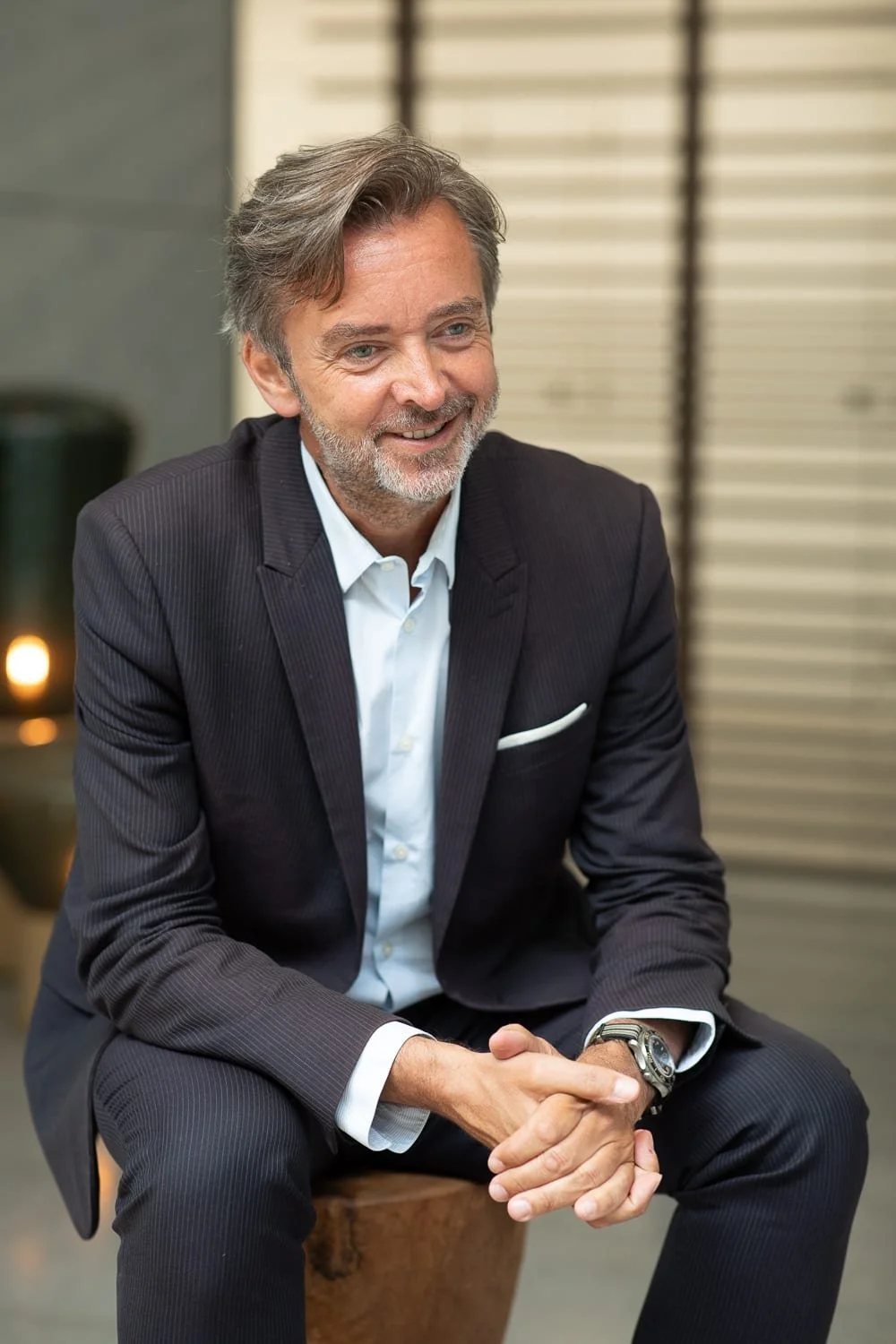 Portrait professionnel d'un dirigeant souriant en costume sombre, assis dans un environnement intérieur aux tons chaleureux