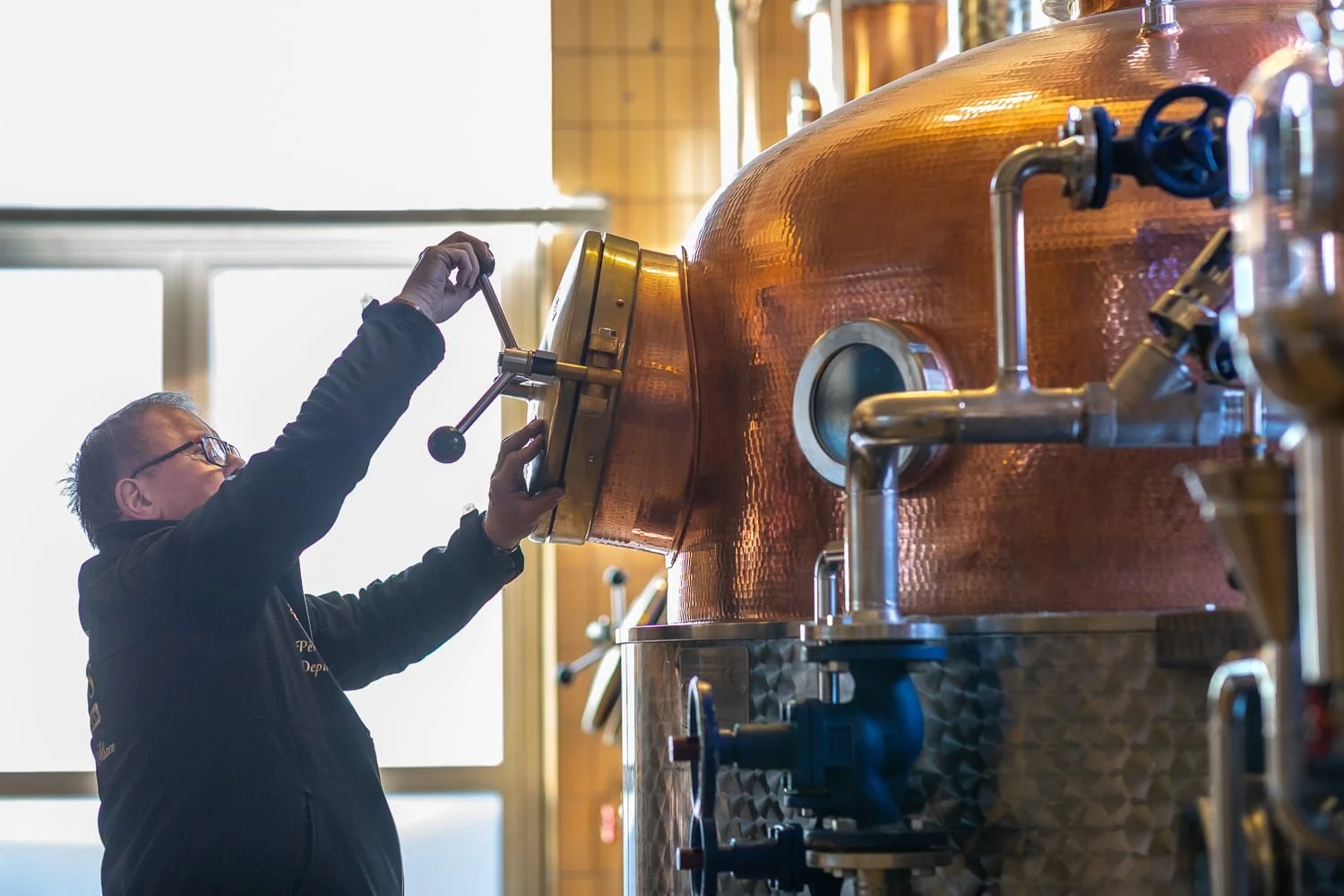 Artisan distillateur manipulant un alambic en cuivre dans une distillerie alsacienne