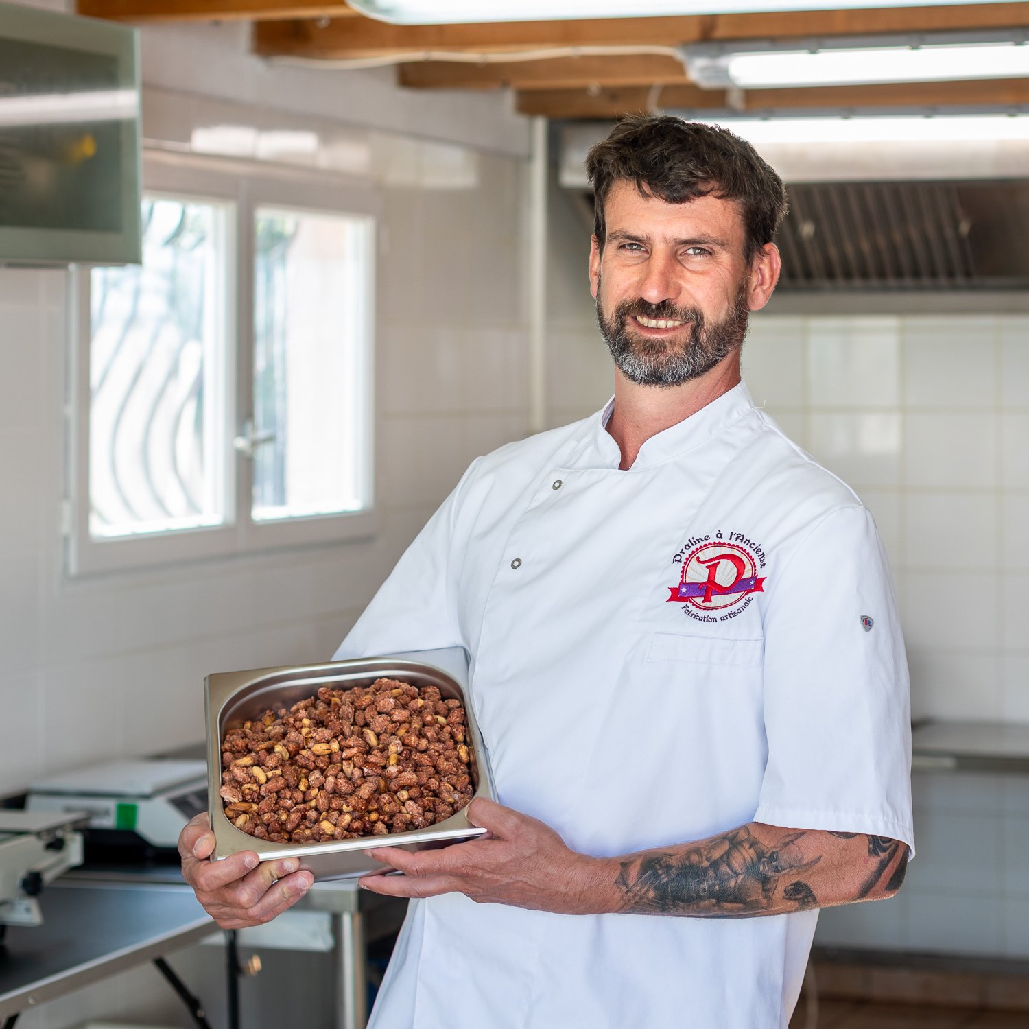portrait de l'artisan tenant un plateau de pralines artisanales