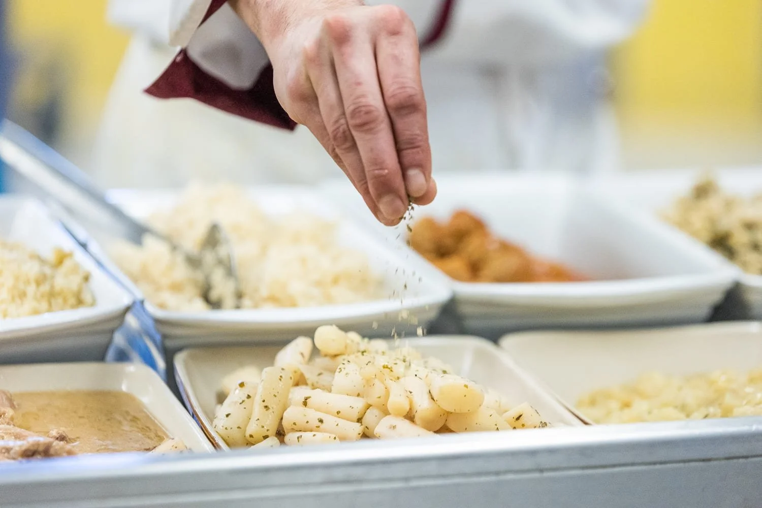 Assaisonnement d'un plat par un chef de cuisine dans le domaine de la restauration collective