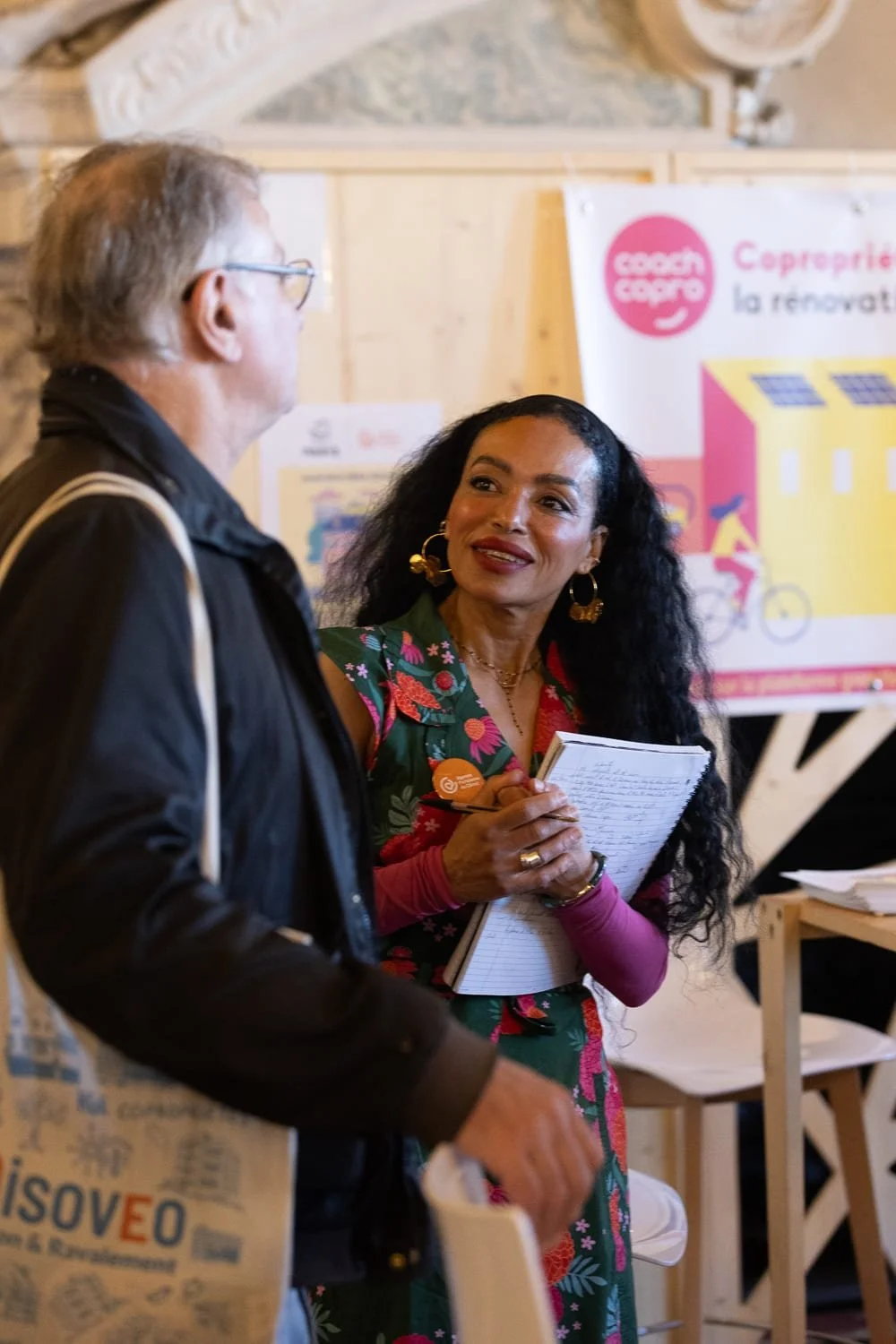 Échanges entre une exposante et un visiteur sur un stand pendant un salon professionnel à Paris.