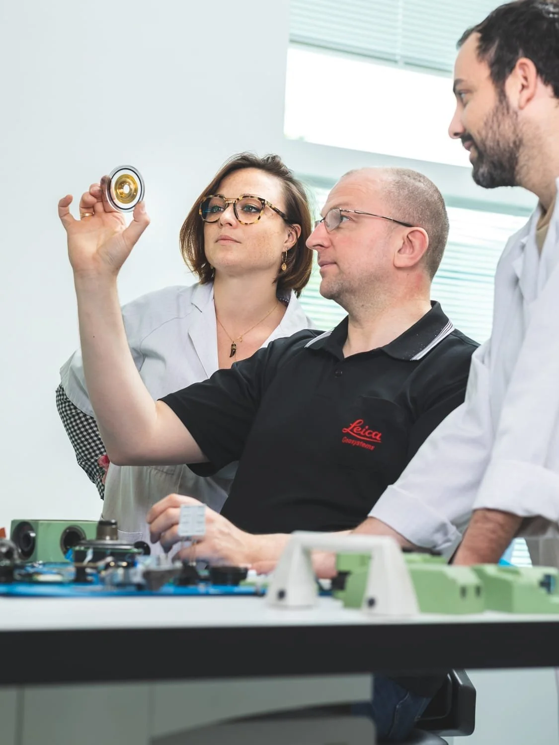 Équipe technique analysant un composant optique en environnement industriel