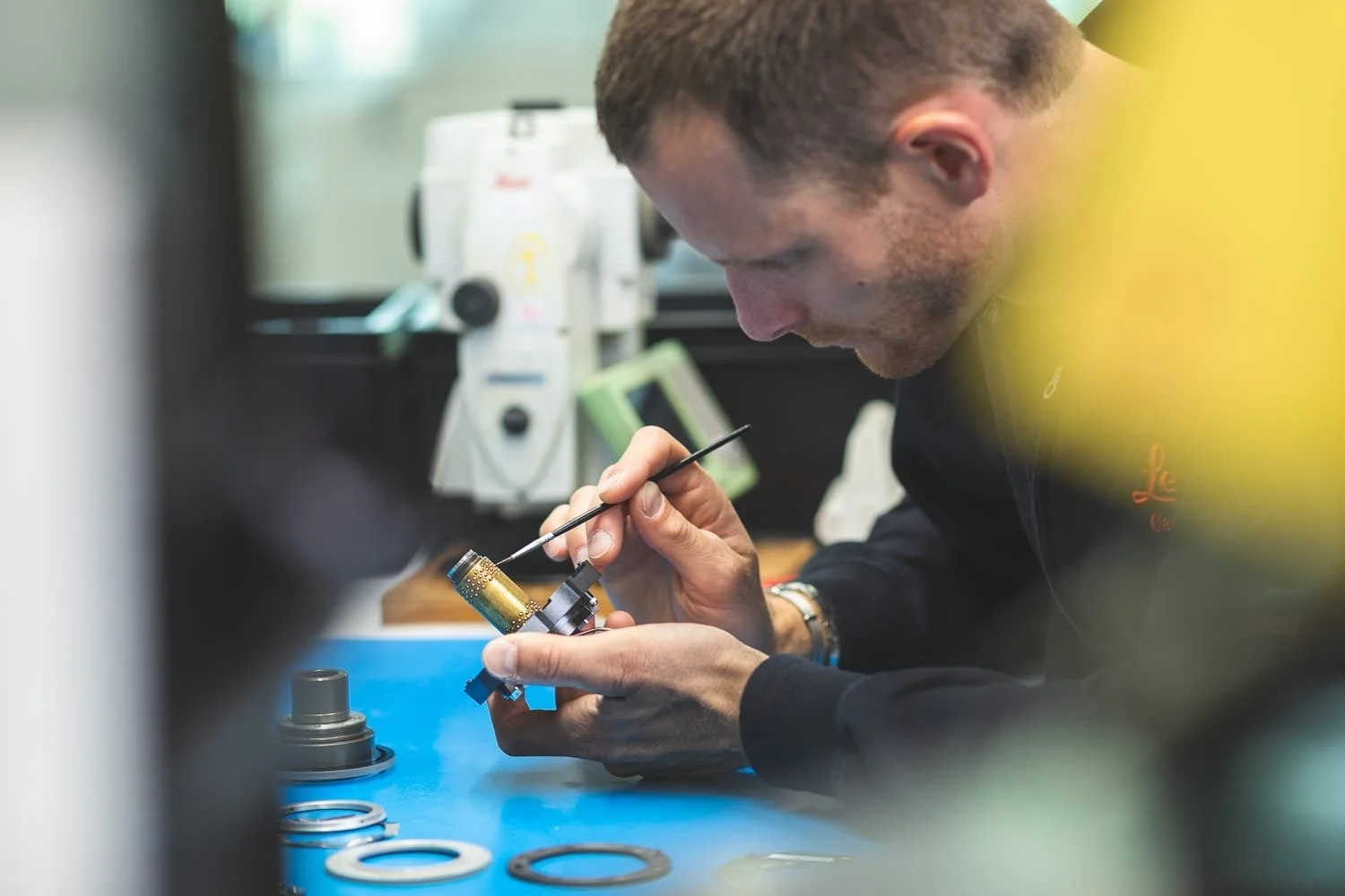 Photographe industriel – technicien nettoyant un instrument de mesure Leica en atelier