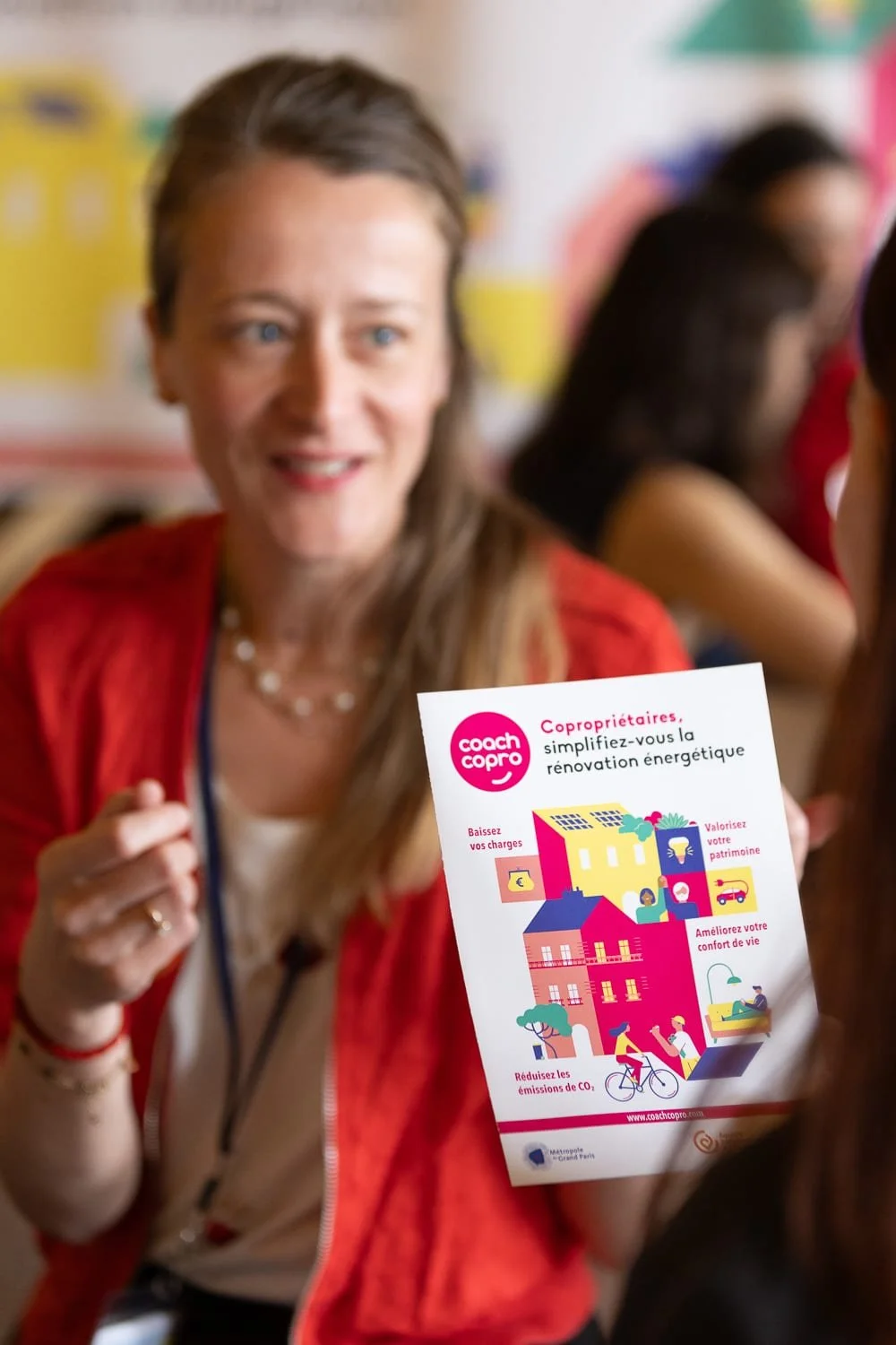 Conseillère présentant des solutions à une visiteuse sur un stand de salon professionnel.