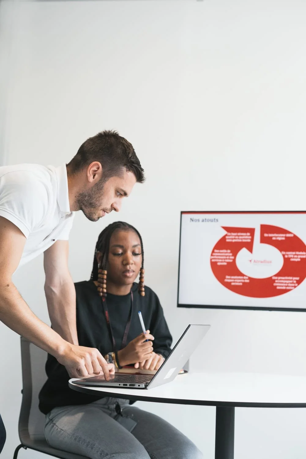 Moment de discussion entre deux collaborateurs autour d'un écran d'ordinateur dans une salle de réunion