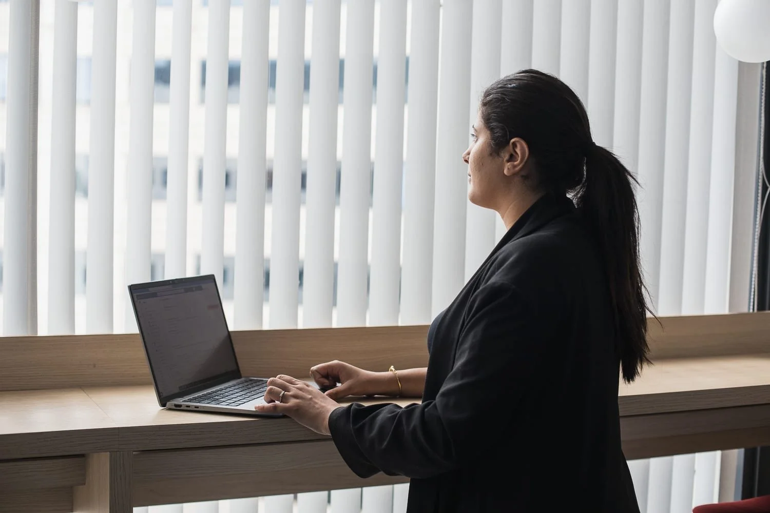 personne en train de regarder par la fenêtre dans un bureau, pendant une phase de réflexion