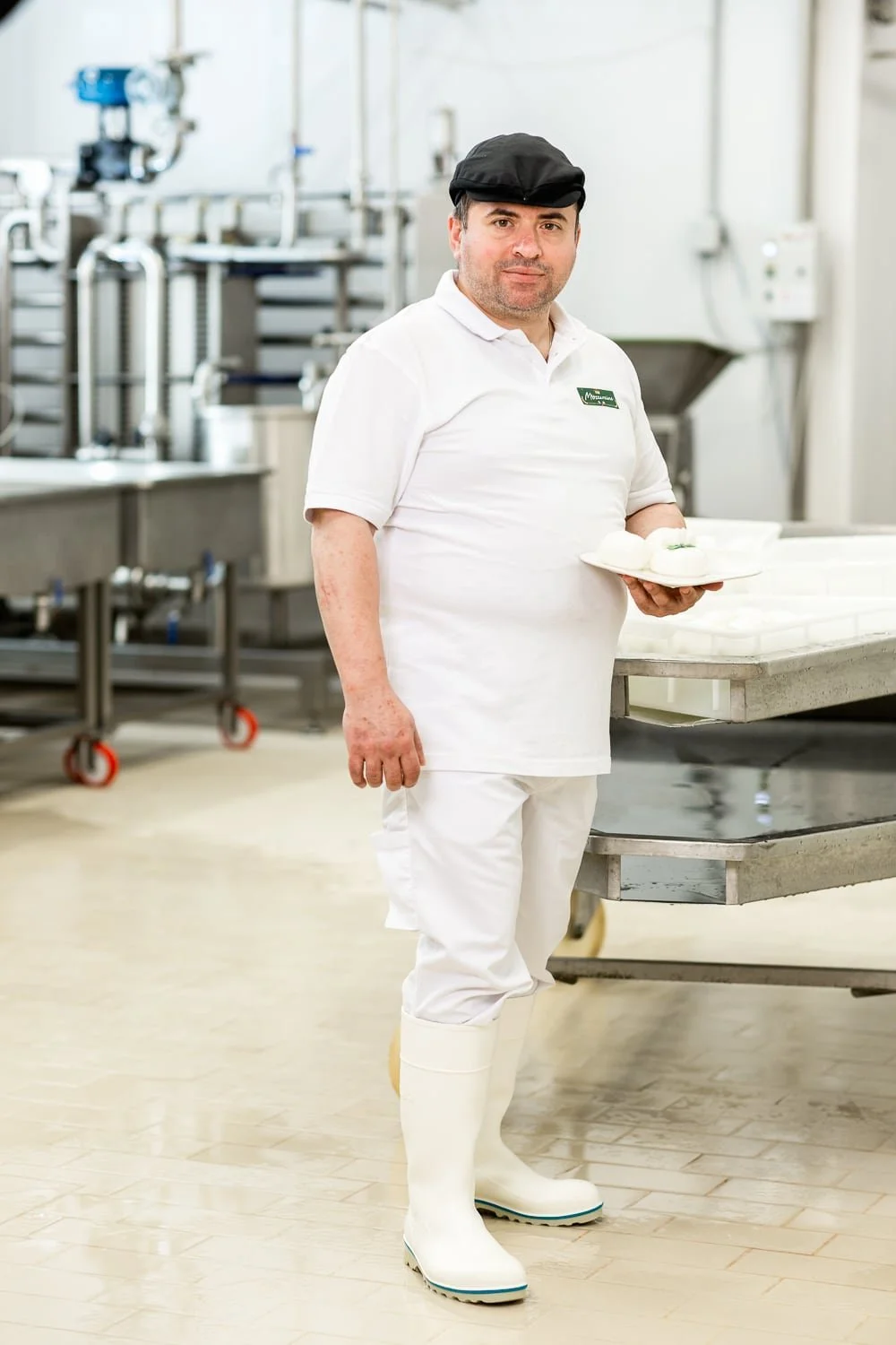 Portrait de l'artisan fromager posant avec une assiette de fromage Mozzarella dans son atelier de production