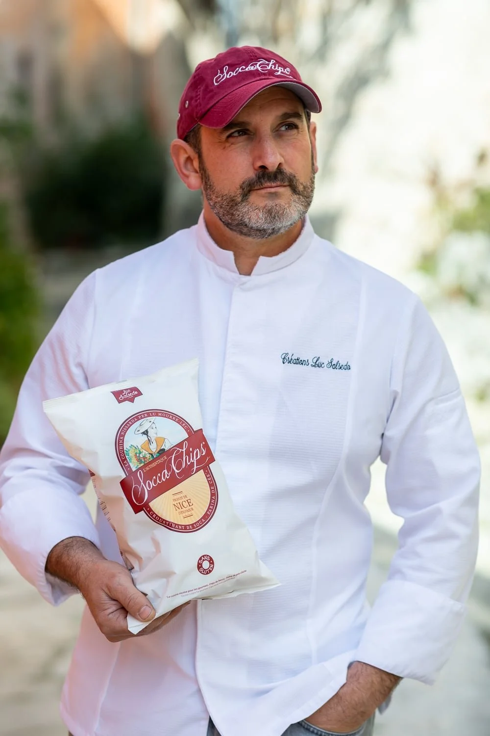 Portrait du producteur posant avec un paquet de chips artisanales Socca chips