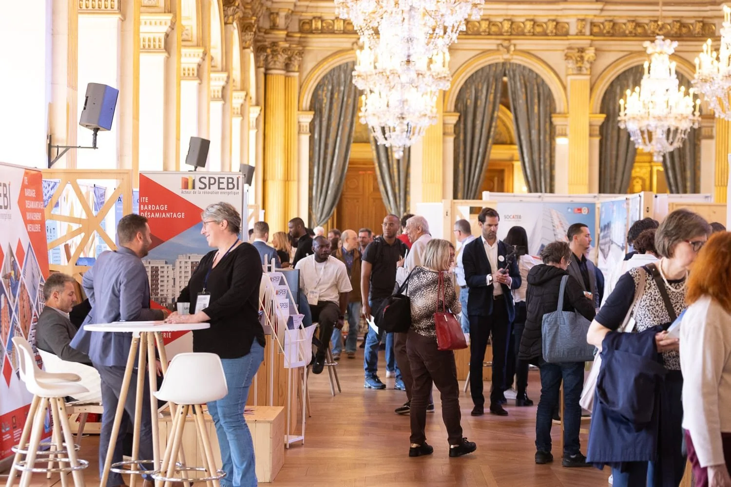 Vue d'ensemble d'un salon professionnel avec exposants et visiteurs en pleine circulation.