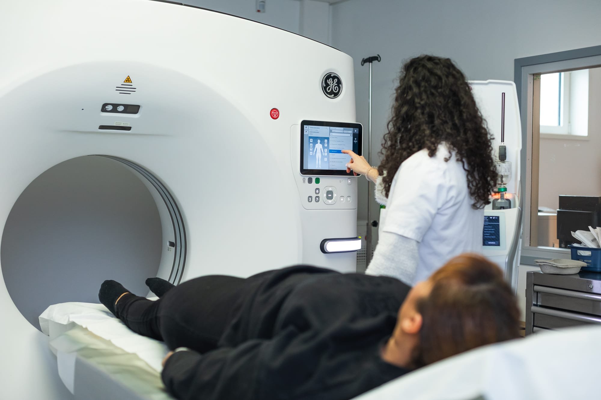 Photographe médical, préparation d’un patient avant un examen scanner dans un centre d’imagerie médicale.