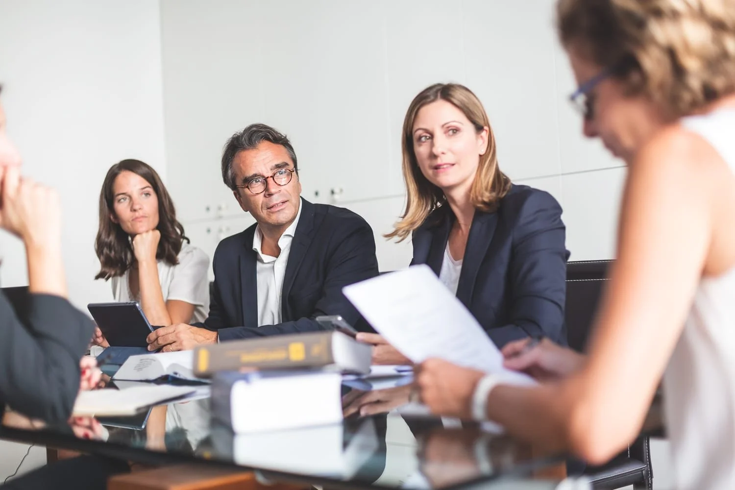 Reportage photo corporate montrant plusieurs personnes en réunion autour d'une table, échangeant dans une salle de conseil