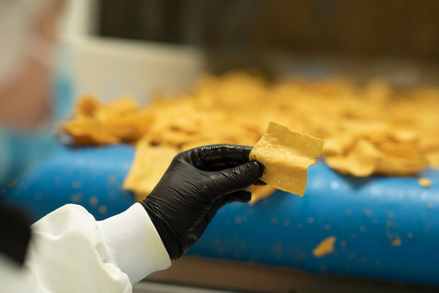 main d’un artisan manipulant les Socca Chips en production