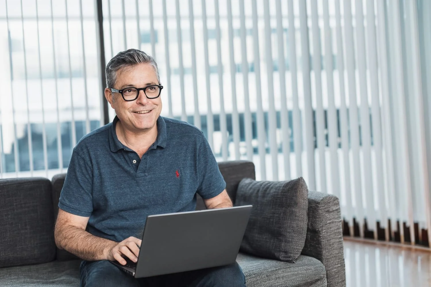 Portrait d’un collaborateur avec son ordinateur sur les genoux dans un espace de détente